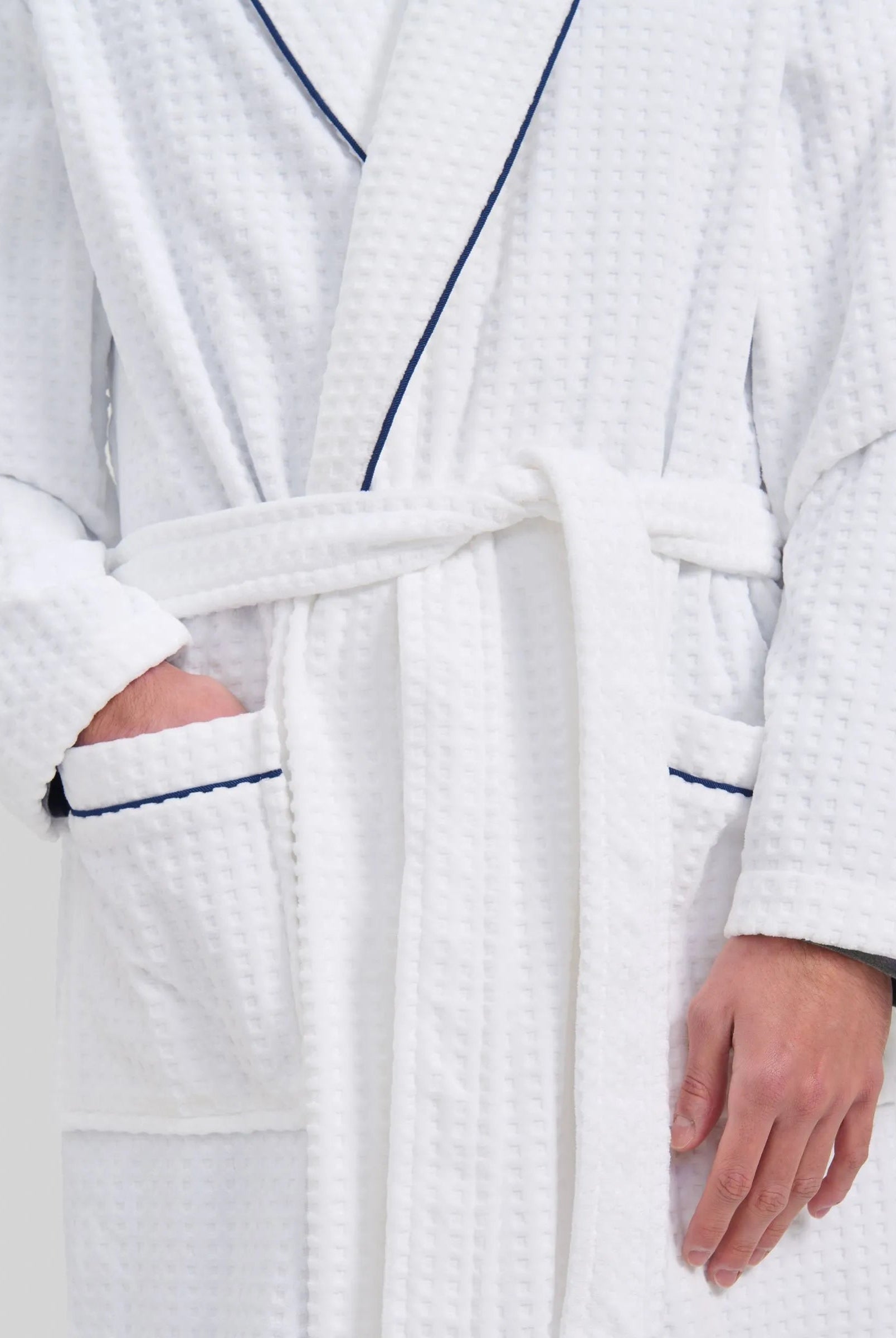 Vista detalle de albornoz blanco de hombre con bolsillos y detalles de vivo azul