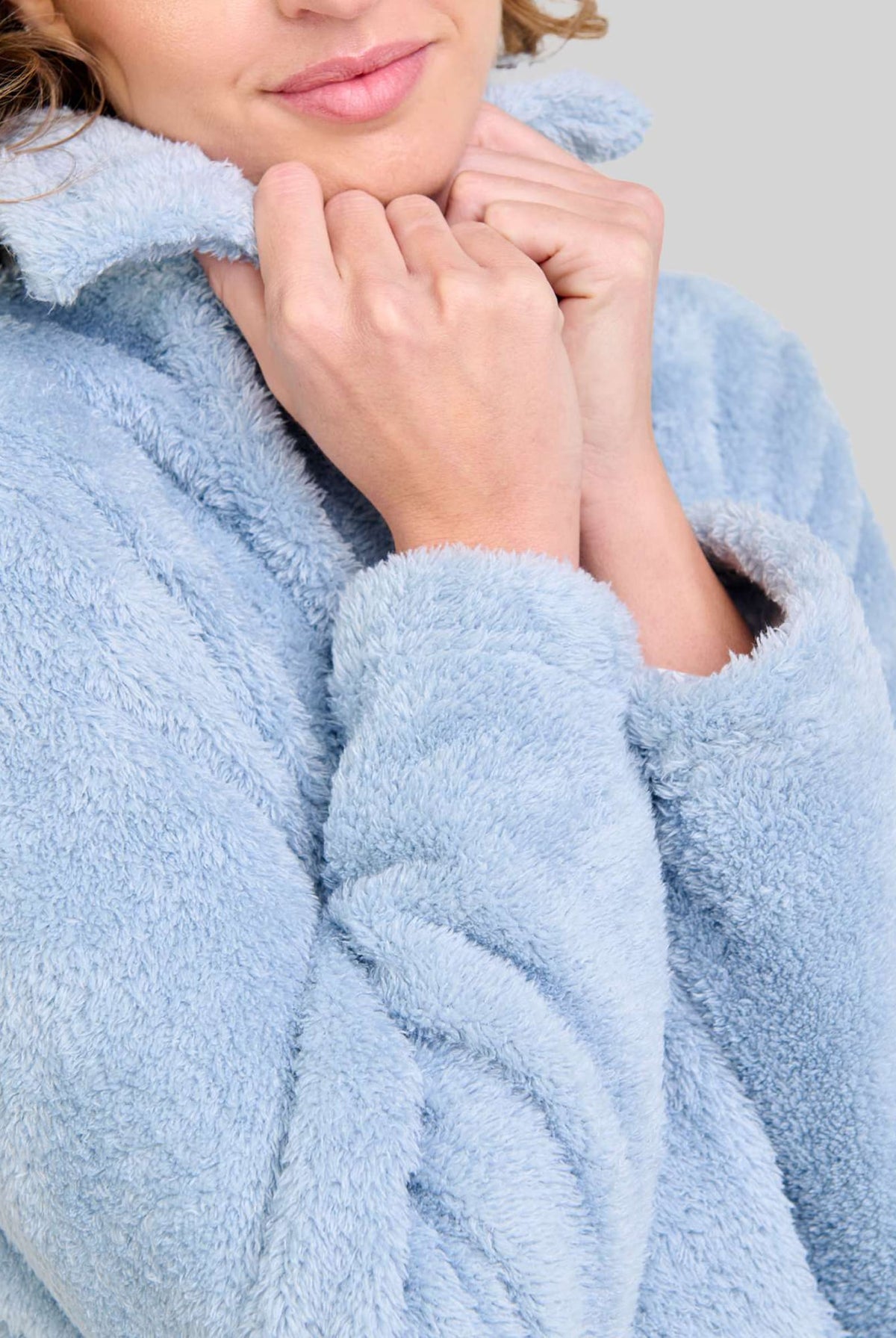 Mujer con bata corta azul afelpada, con botones y cuello clásico moda de invierno para hogar.