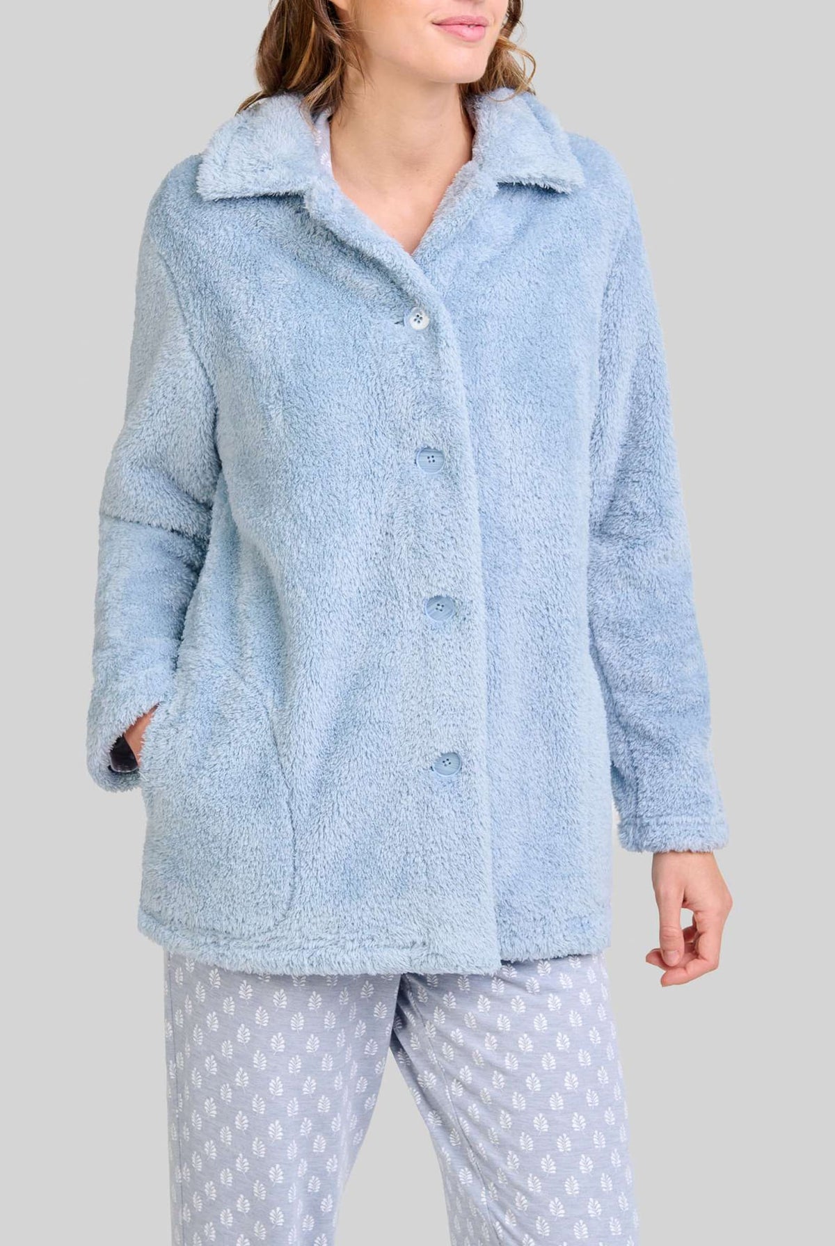 Mujer luce cómoda y actual bata corta de rizo azul acero abotonada con bolsillos