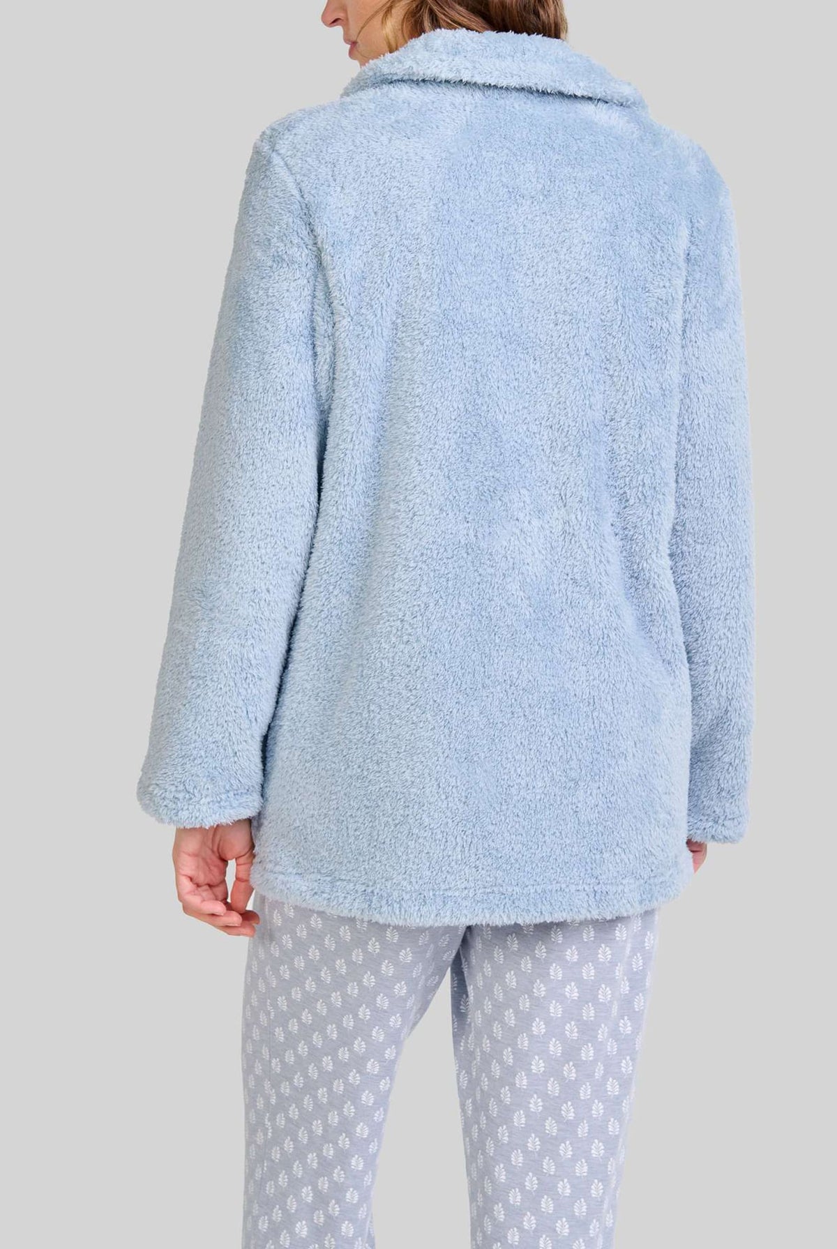 Mujer de espaldas con bata cálida de rizo azul claro ideal para invierno