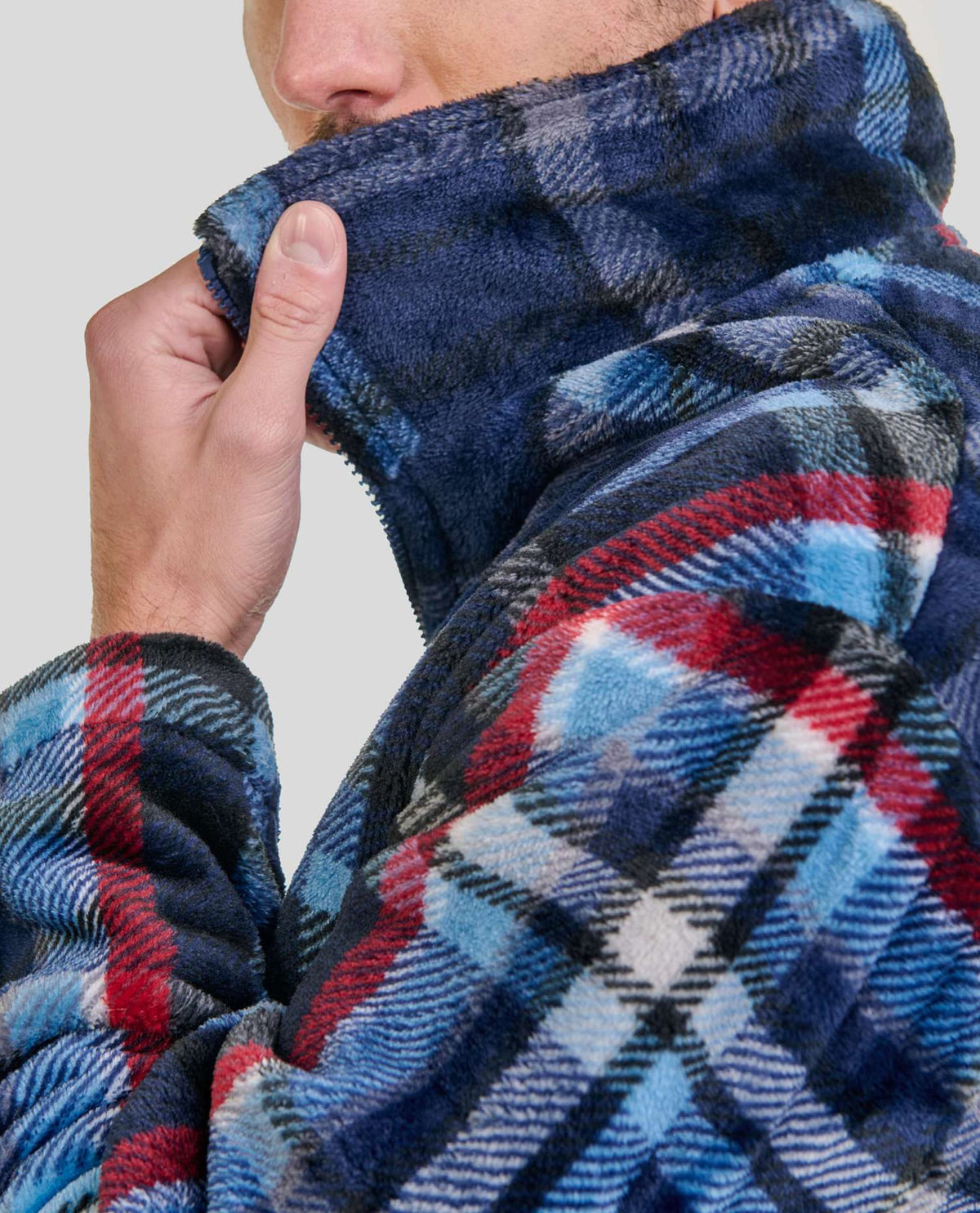 Hombre sujetando el cuello de su agradable bata polar corta de cuadros para invierno