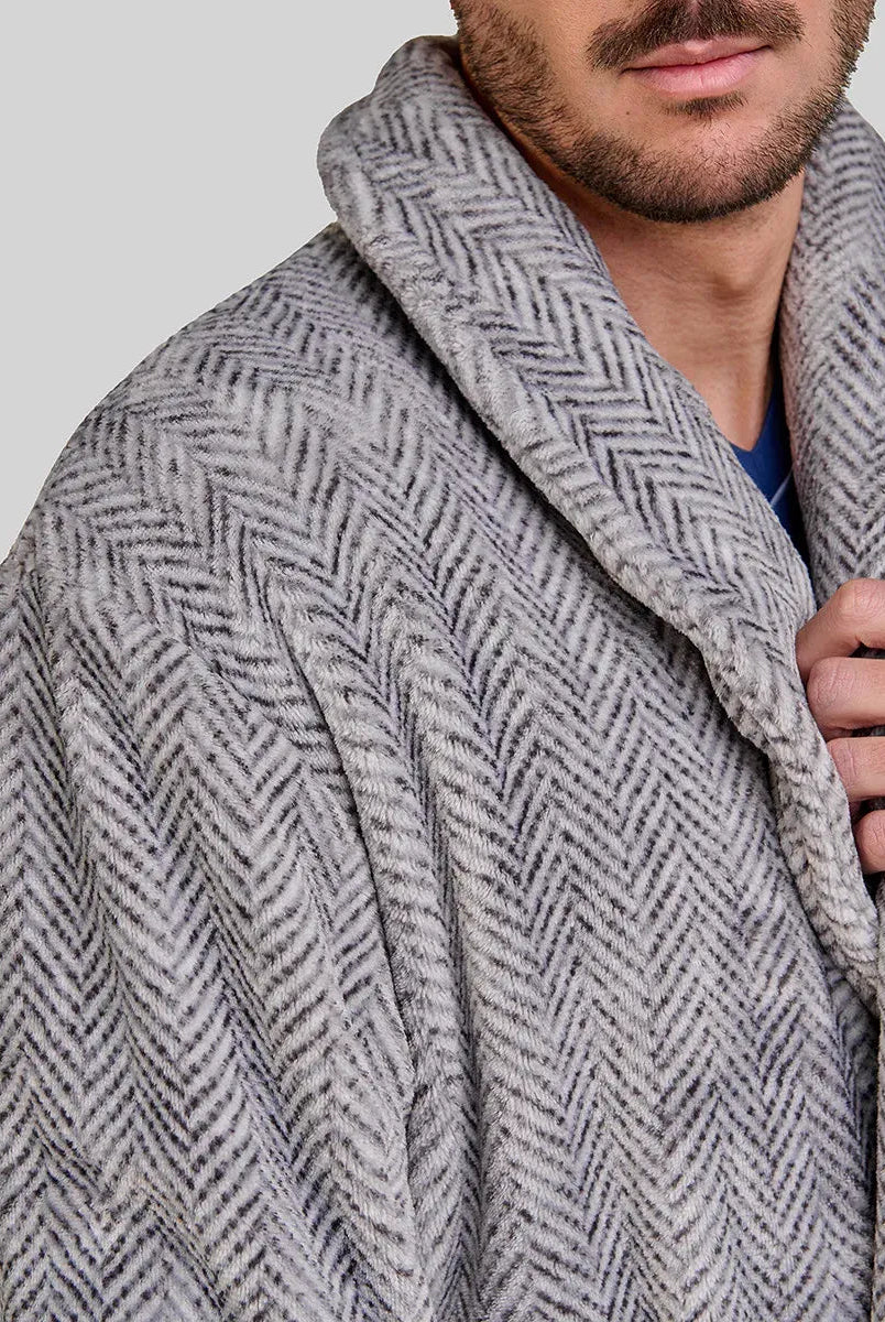 Elegante hombre sujetando el cuello smoking de su bata gris de diseño espiga