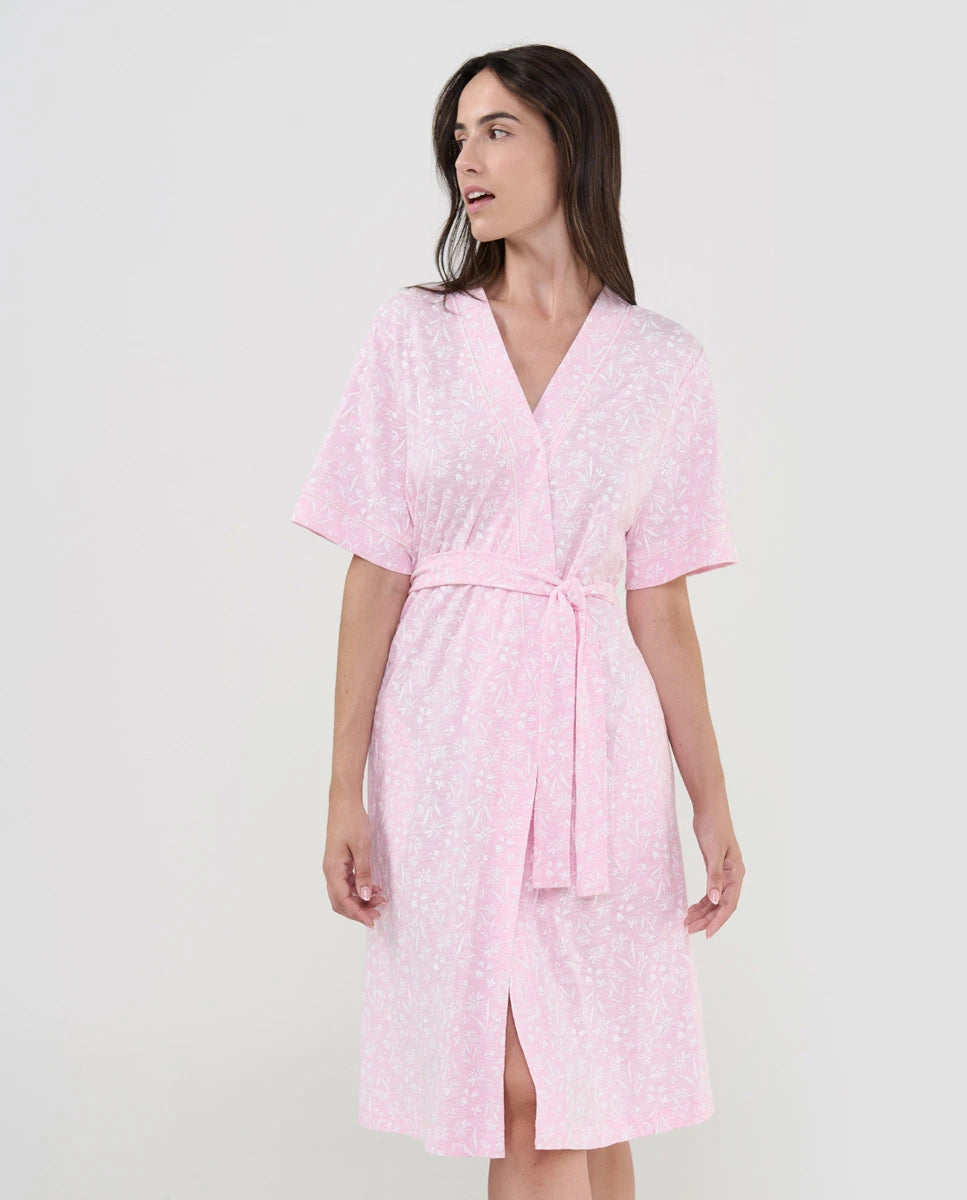 Mujer con bata veraniega corta en punto rosa con estampado florecitas blancas y vivo en solapa
