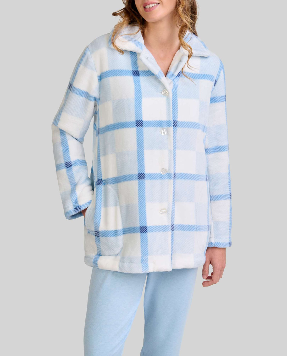 mujer luce bata corta de cuadros azul y blanco con botones y bolsillos laterales