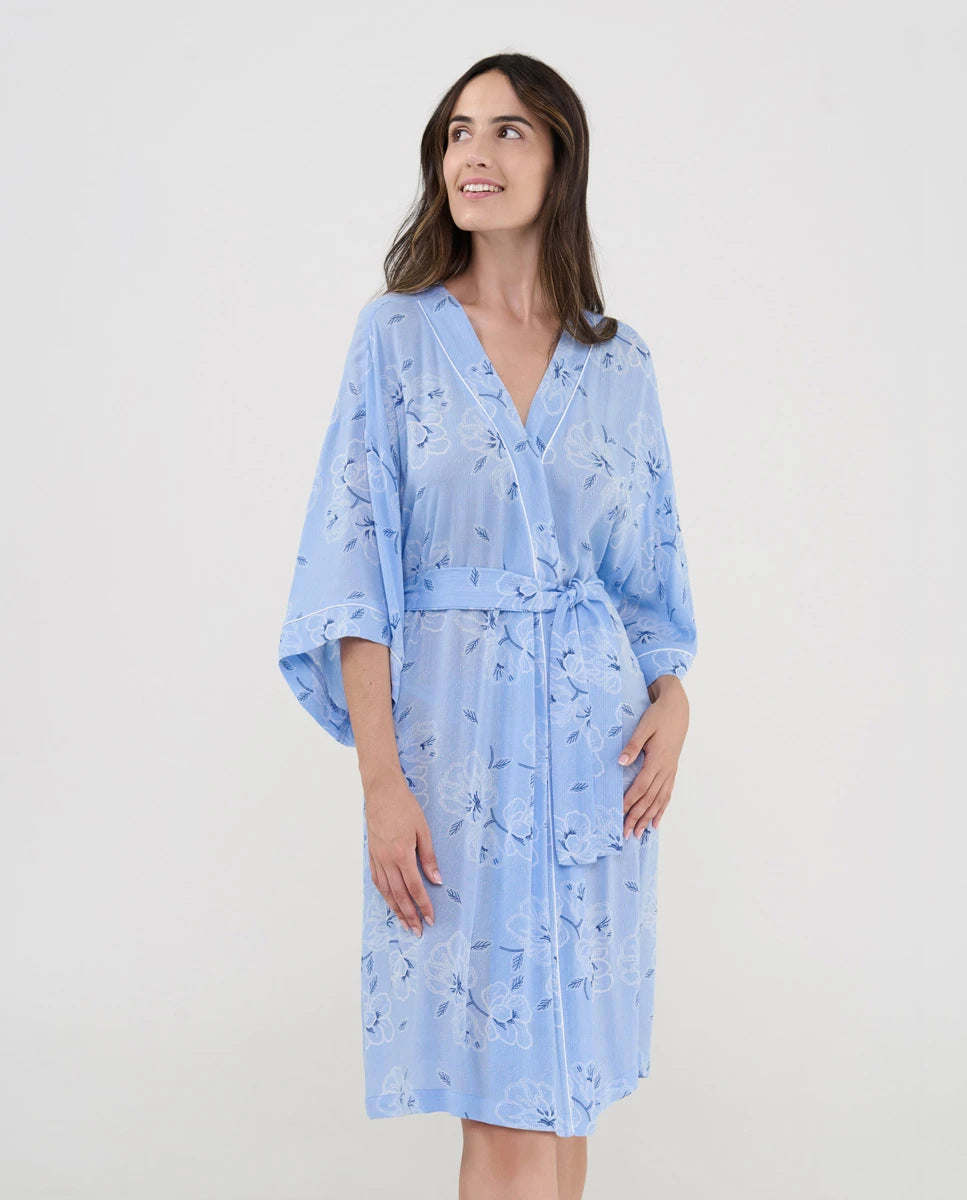 Mujer luce ligera y confortable bata corta de verano cruzada estampado celeste de flores