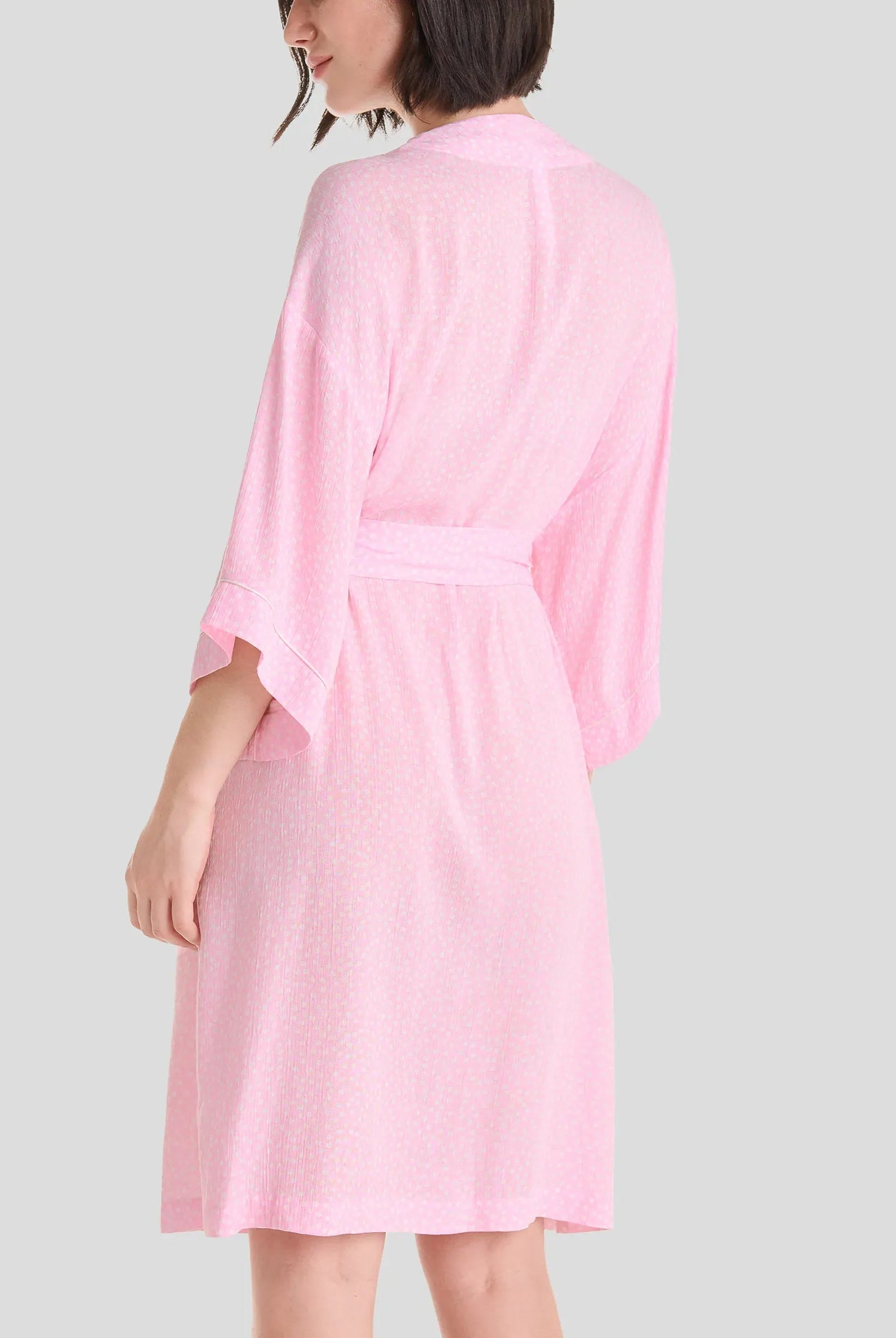 Mujer de espaldas luce elegante bata de verano con manga francesa en color rosa a topitos, con cinturón y bolsillos laterales - Rosa