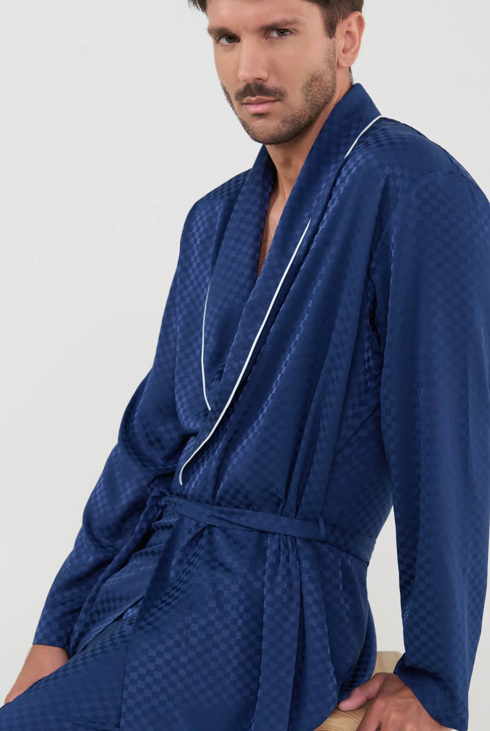 Primer plano del tejido jacquard marino de la bata Lohe, revelando el exquisito patrón de cuadros y la calidad premium.