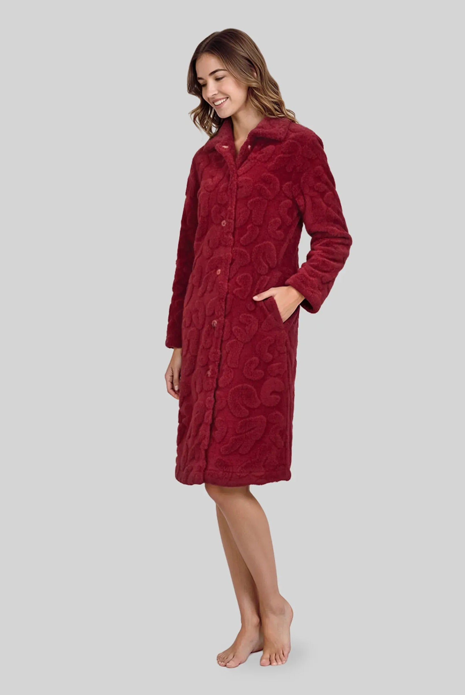 Mujer con bata larga de invierno abotonada y con bolsillos en amoroso tejido jacquard granate