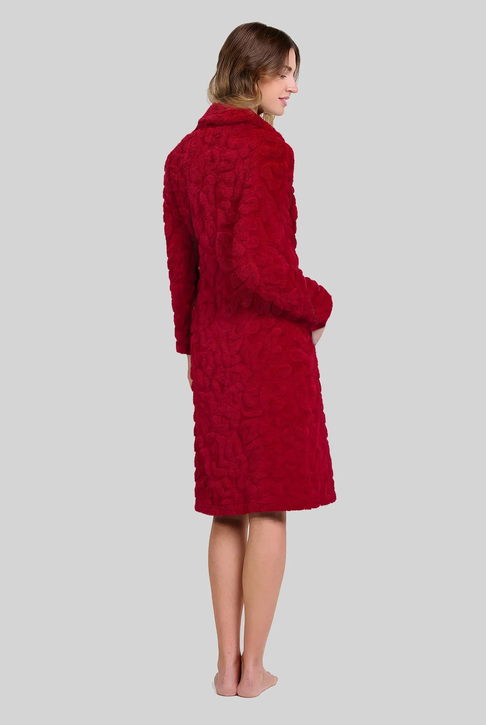 Mujer de espaldas luce bata abotonada y con bolsillos en jacquard granate para el invierno