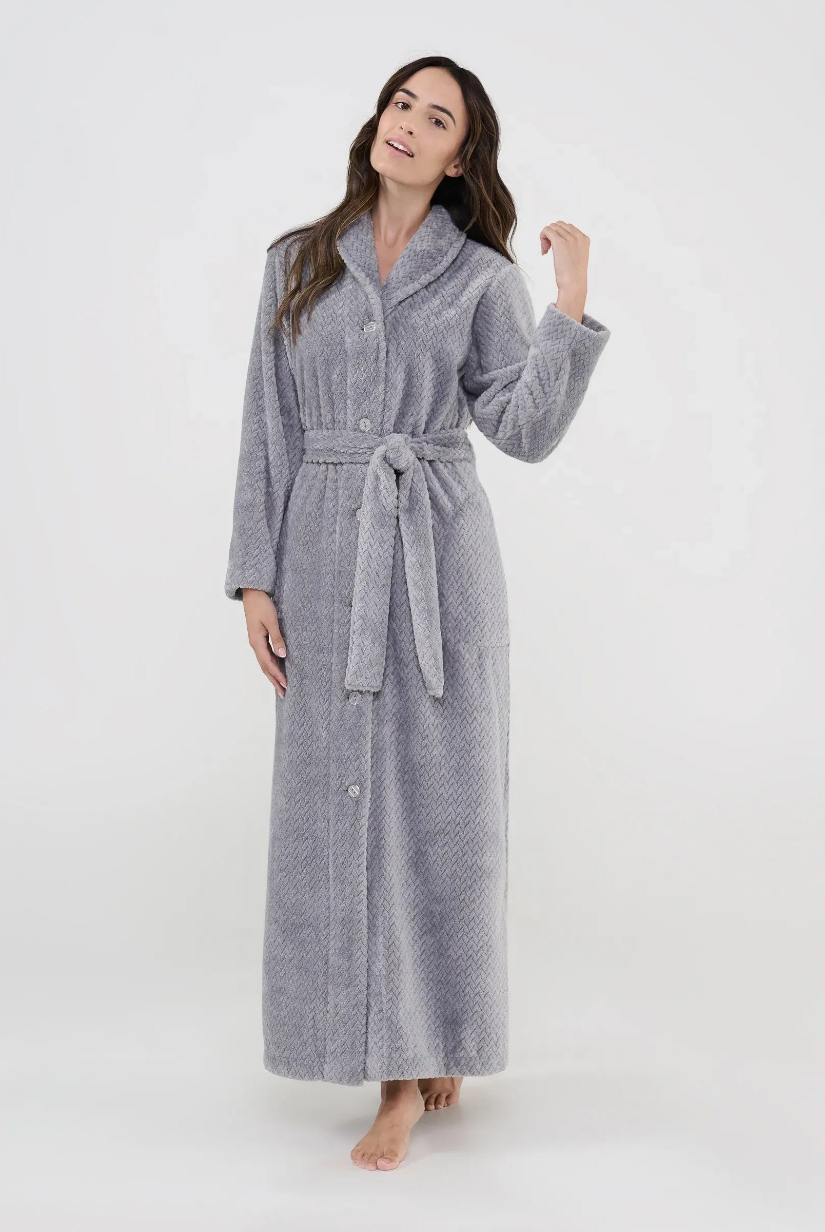 Mujer luce bata larga gris jacquard con botones, cinturón y bolsillos laterales