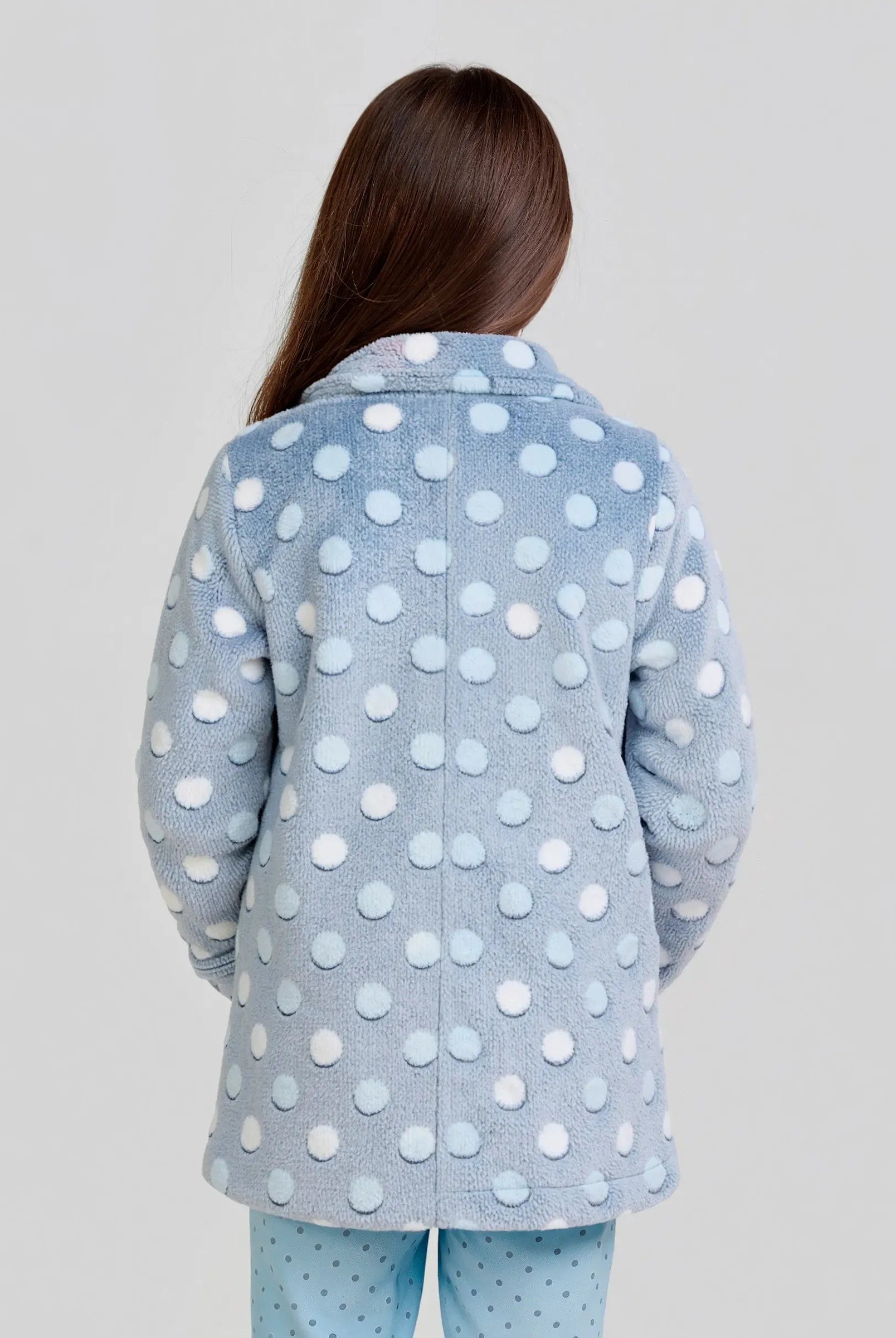 Vista lateral de niña posando con bata infantil de invierno estampada azul con círculos en relieve