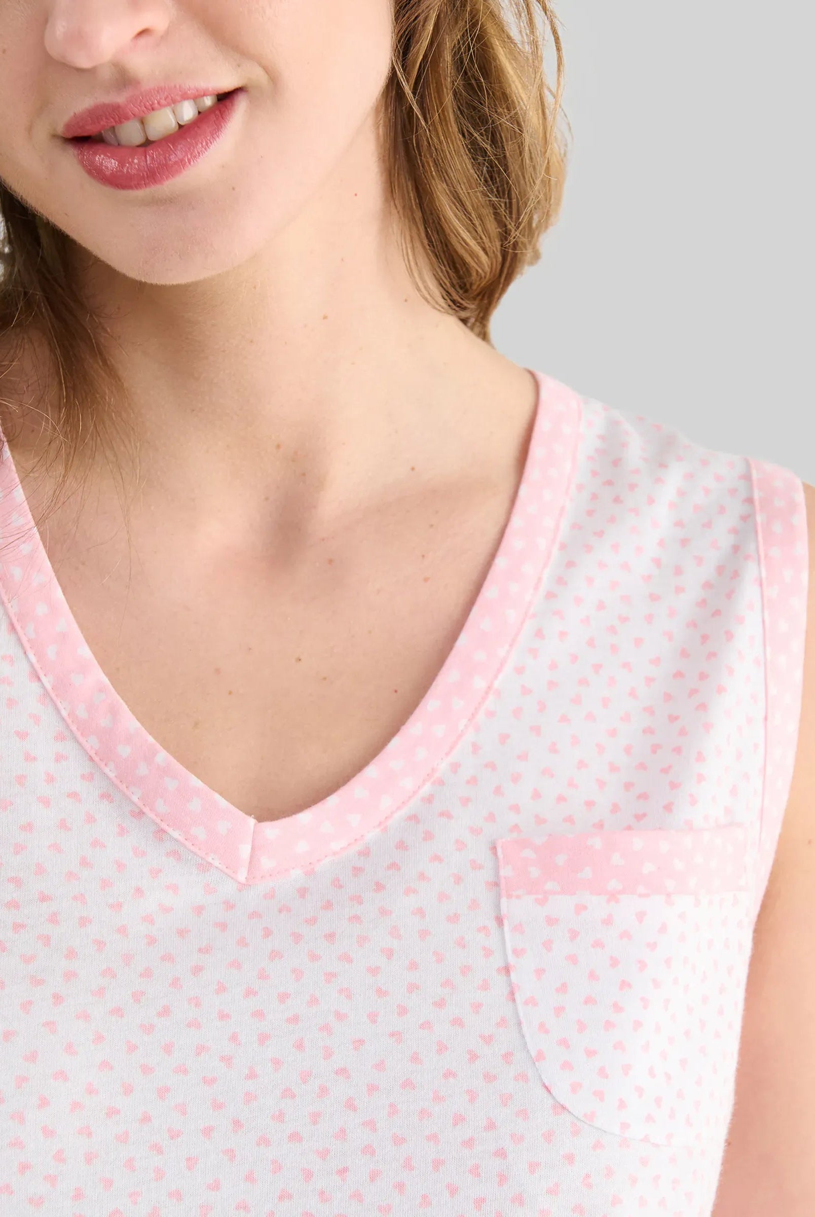Mujer luce camisón lencero sin mangas de canalé rosa para verano con cuello abierto y entredos