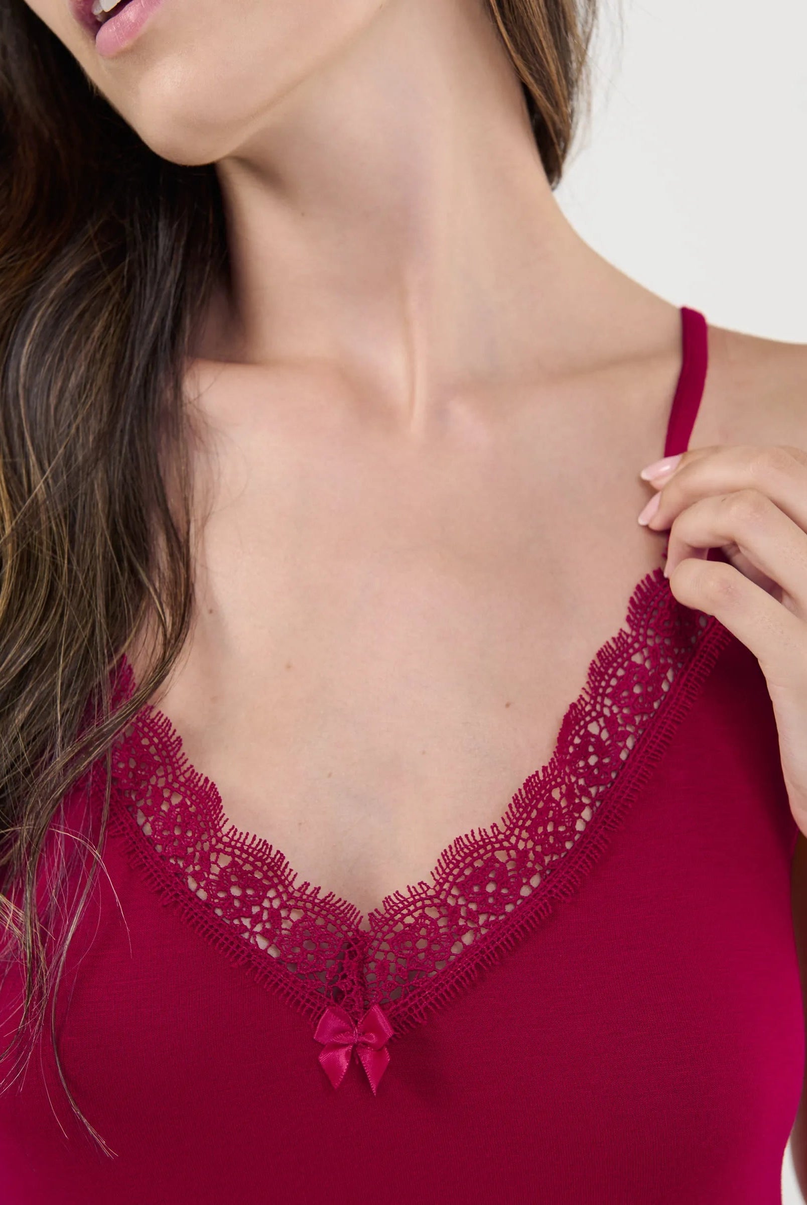 Primer plano detallado del exquisito encaje y el adorno de lazo en el cuello en V del camisón modal.