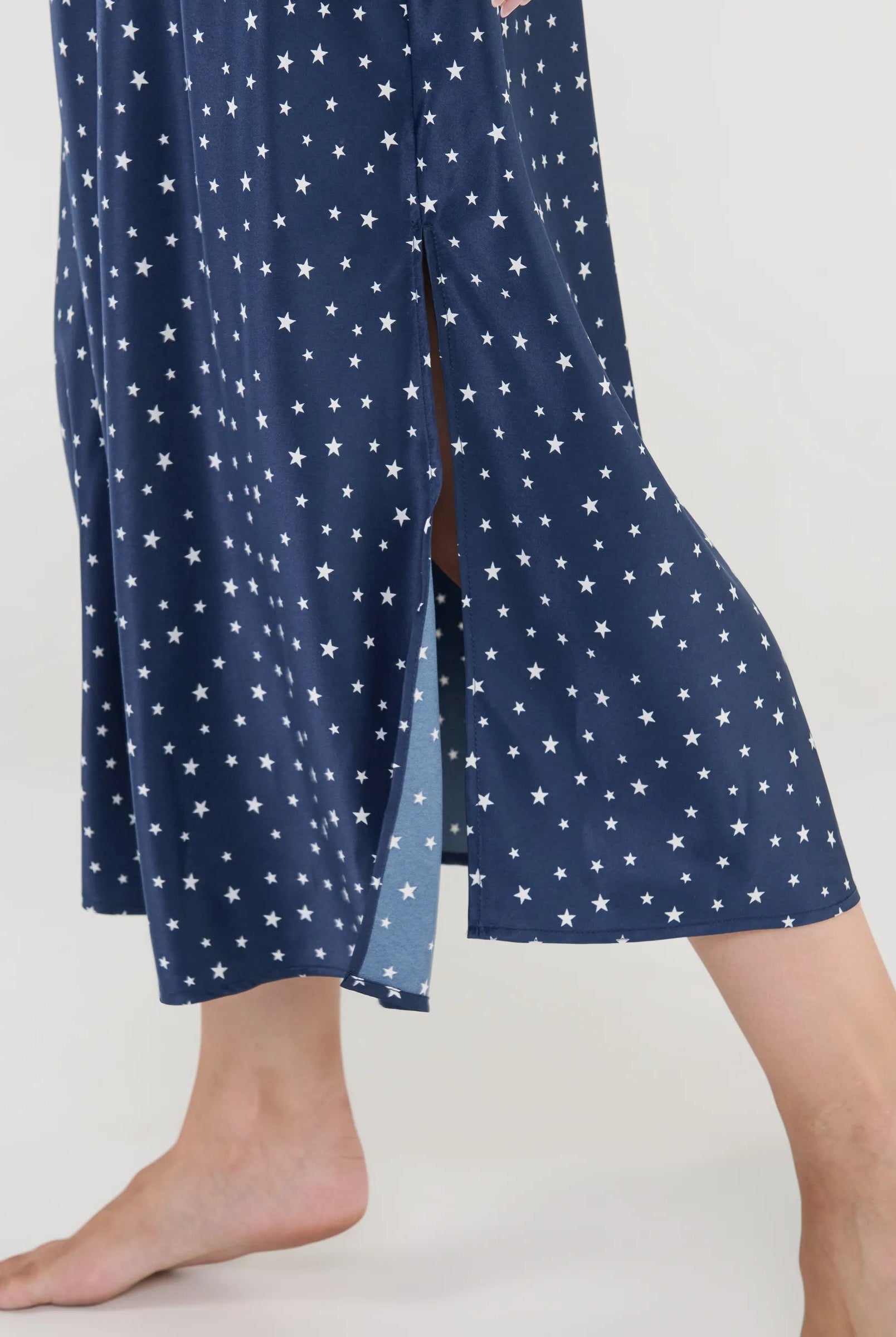 Primer plano del delicado tejido de raso con estampado de estrellas y finos tirantes regulables.