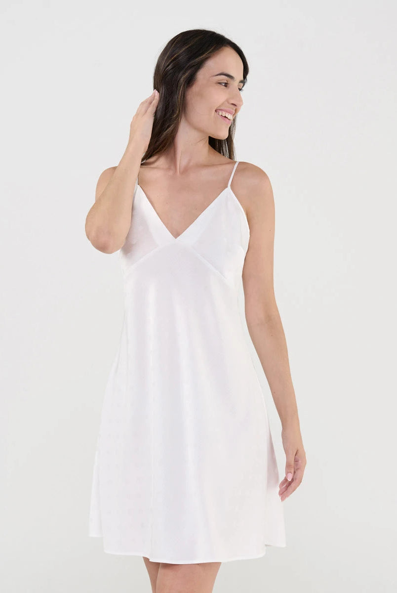 Mujer luce camisón lencero de suave tejido plana marfil con topos de raso, escote pico y tirantes