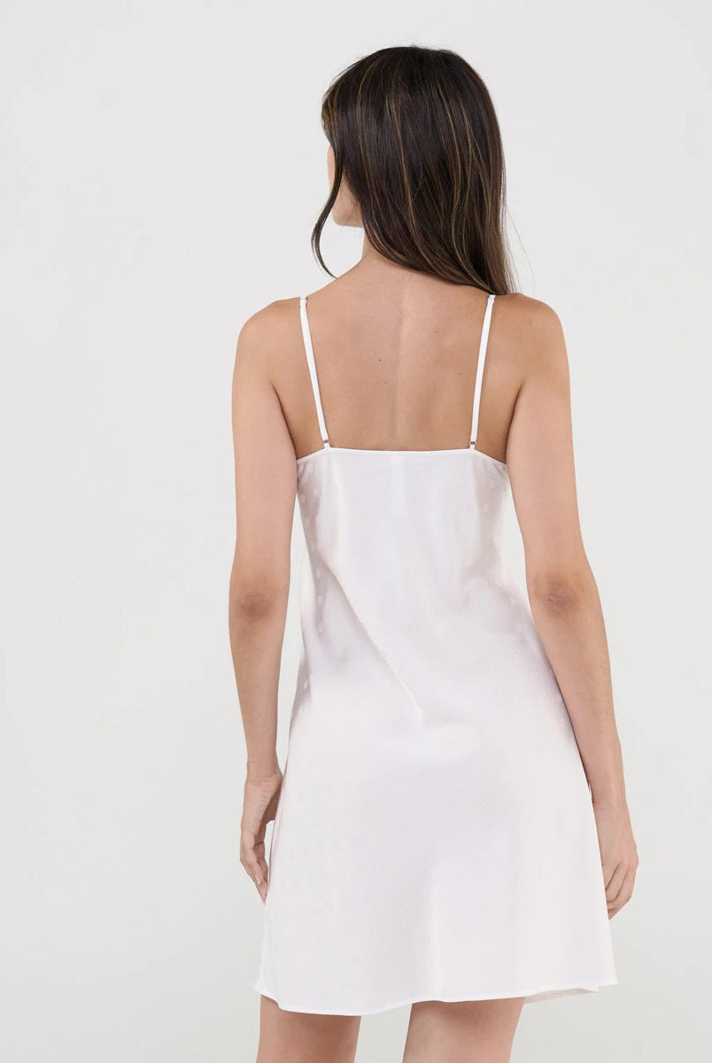 Vista de espaldas de mujer con sensual camisón corto de tirantes color marfil