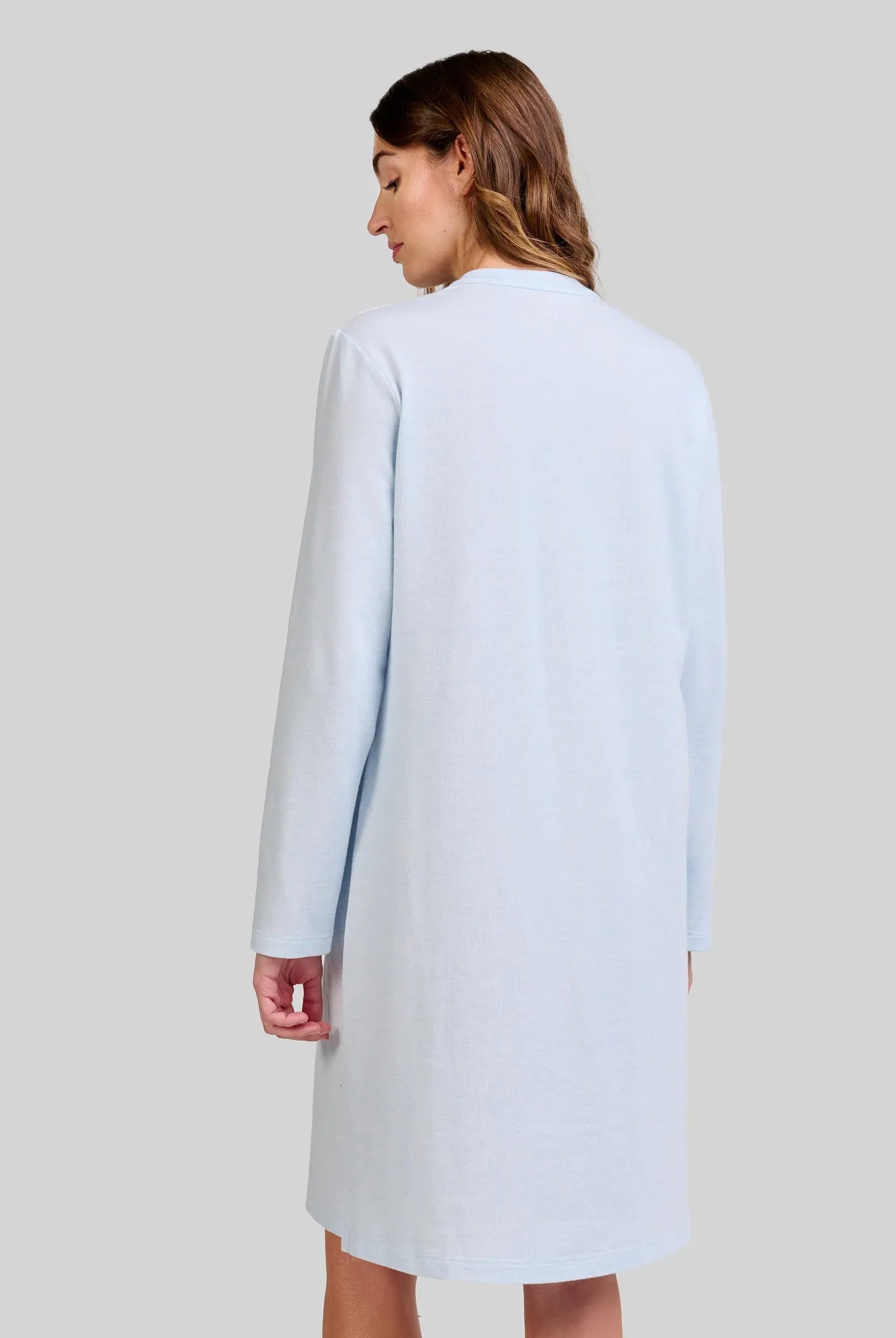 Mujer de espaldas con elegante camisola de invierno celeste de manga larga