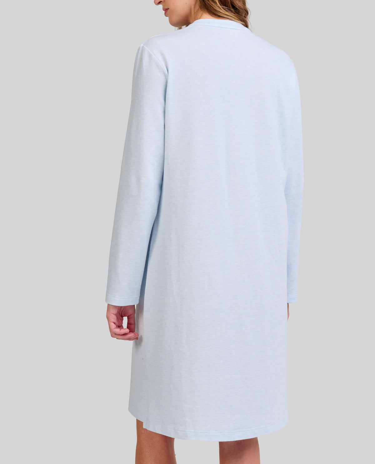 Mujer de espaldas con elegante camisola de invierno celeste de manga larga