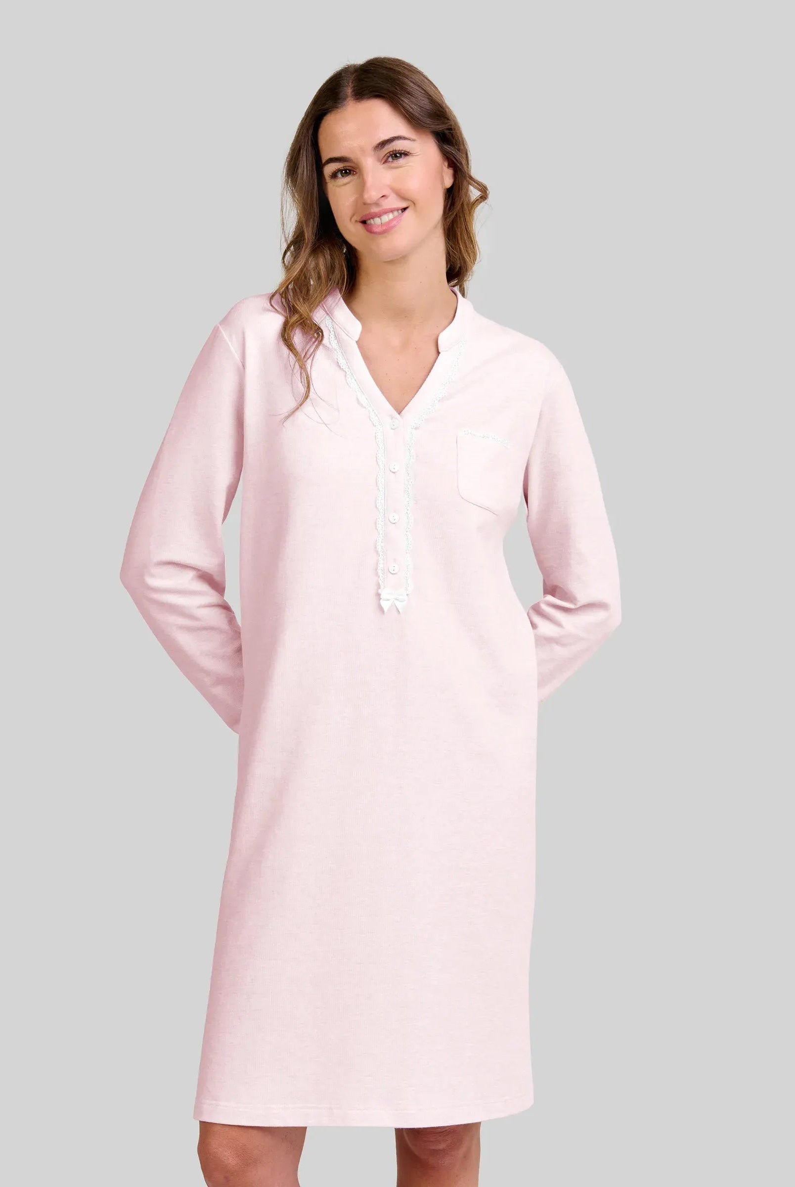 Mujer posa con su camisón de vigoré rosa claro con ribetes blancos y cuello pico abotonado