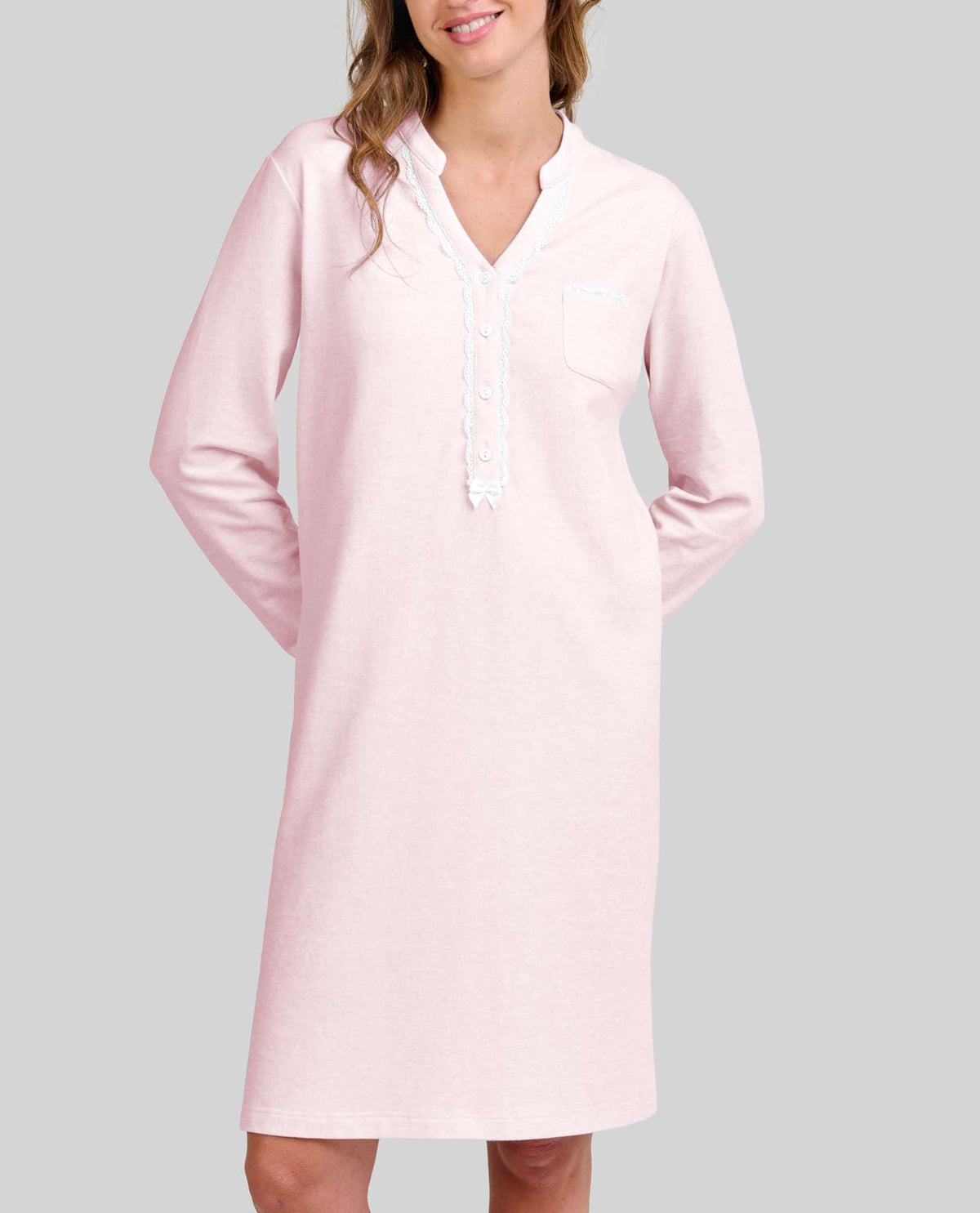 Mujer posa con su camisón de vigoré rosa claro con ribetes blancos y cuello pico abotonado