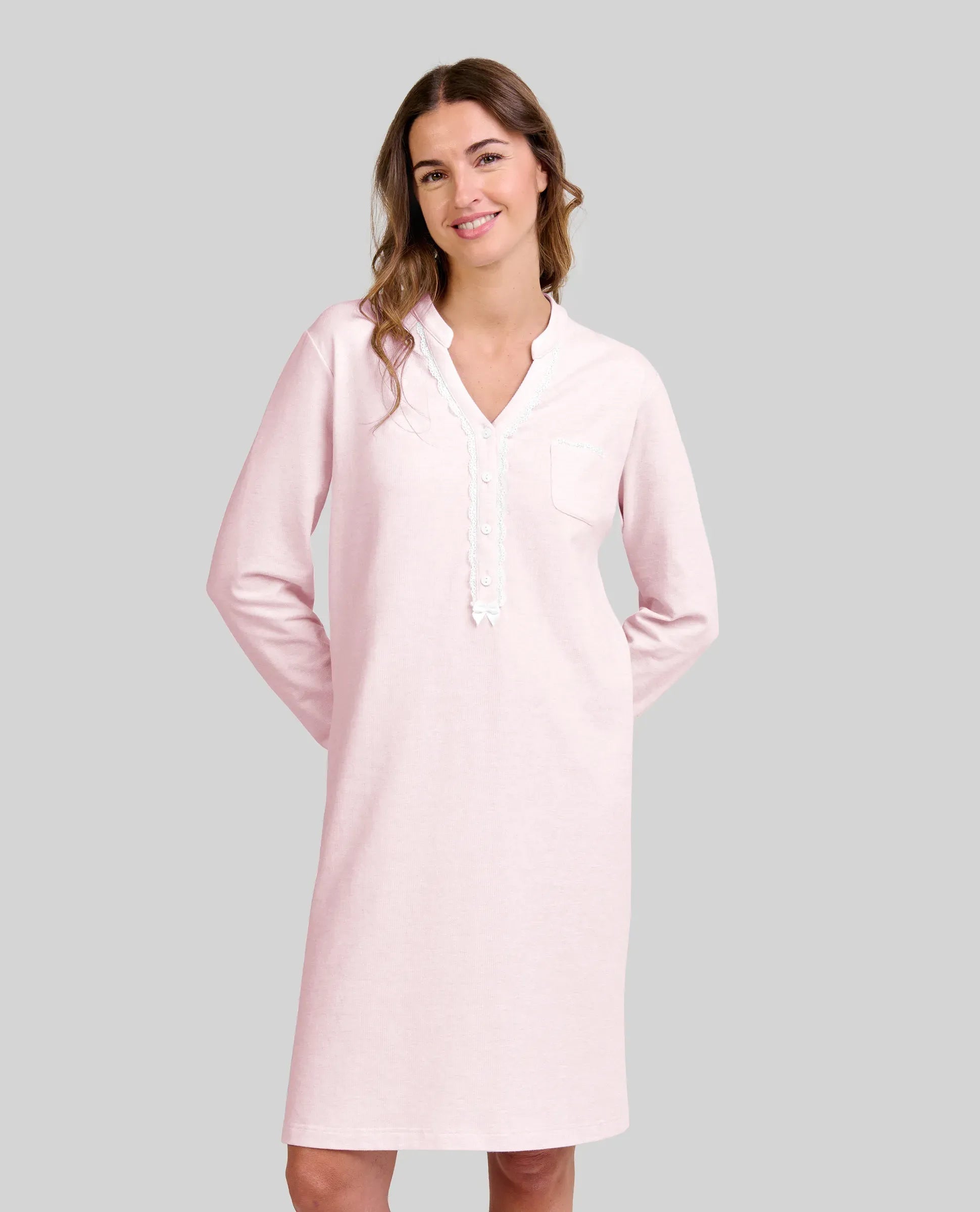 Mujer posa con su camisón de vigoré rosa claro con ribetes blancos y cuello pico abotonado