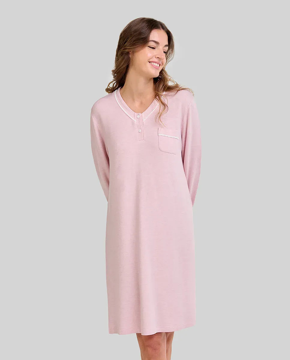 Mujer posa con camisón rosa vigoré de manga larga, bolsillo en el pecho y escote abotonado ideal para dormir.
