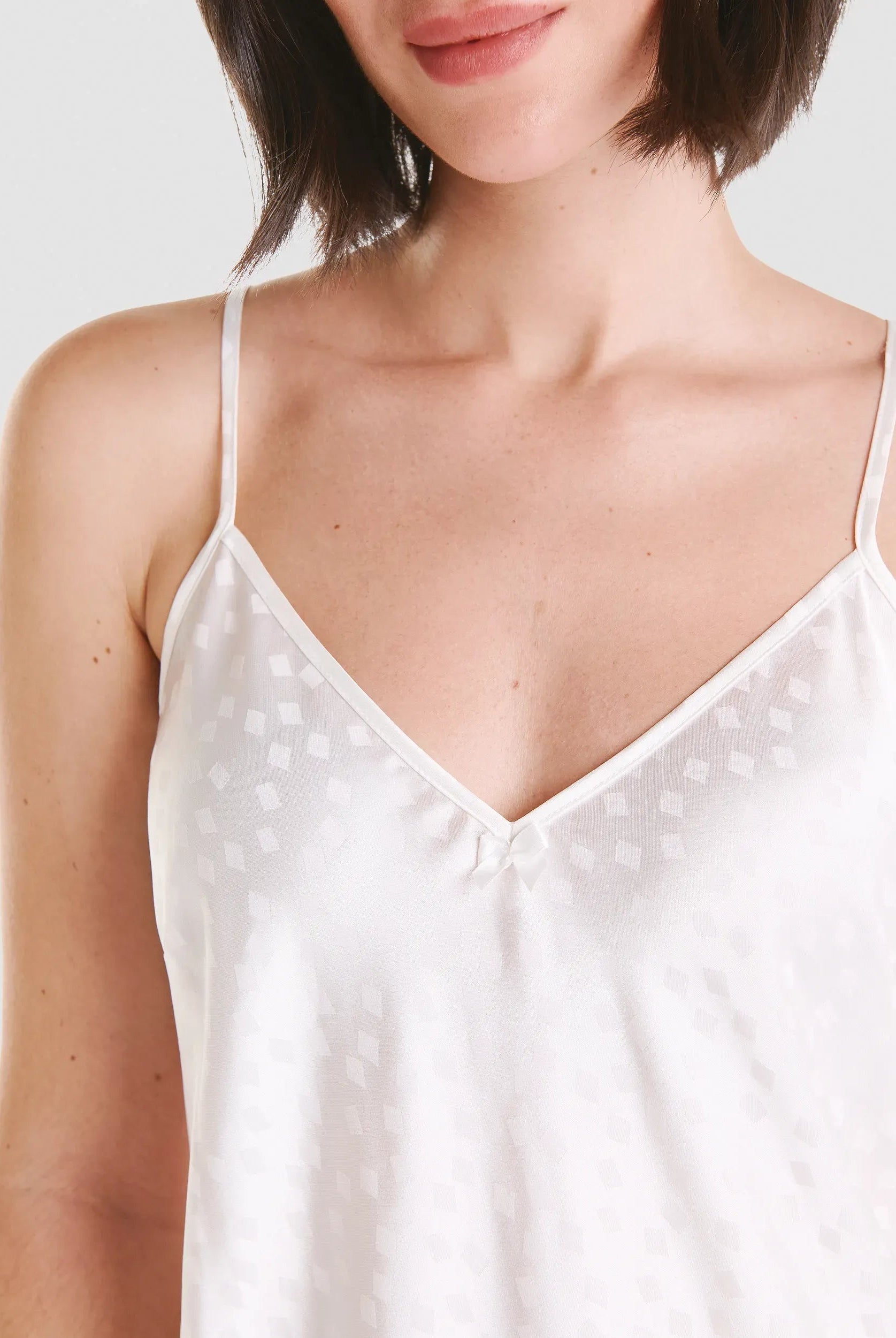 Vista detalle de escote en pico de camisón con tirantes en raso marfil jacquard
