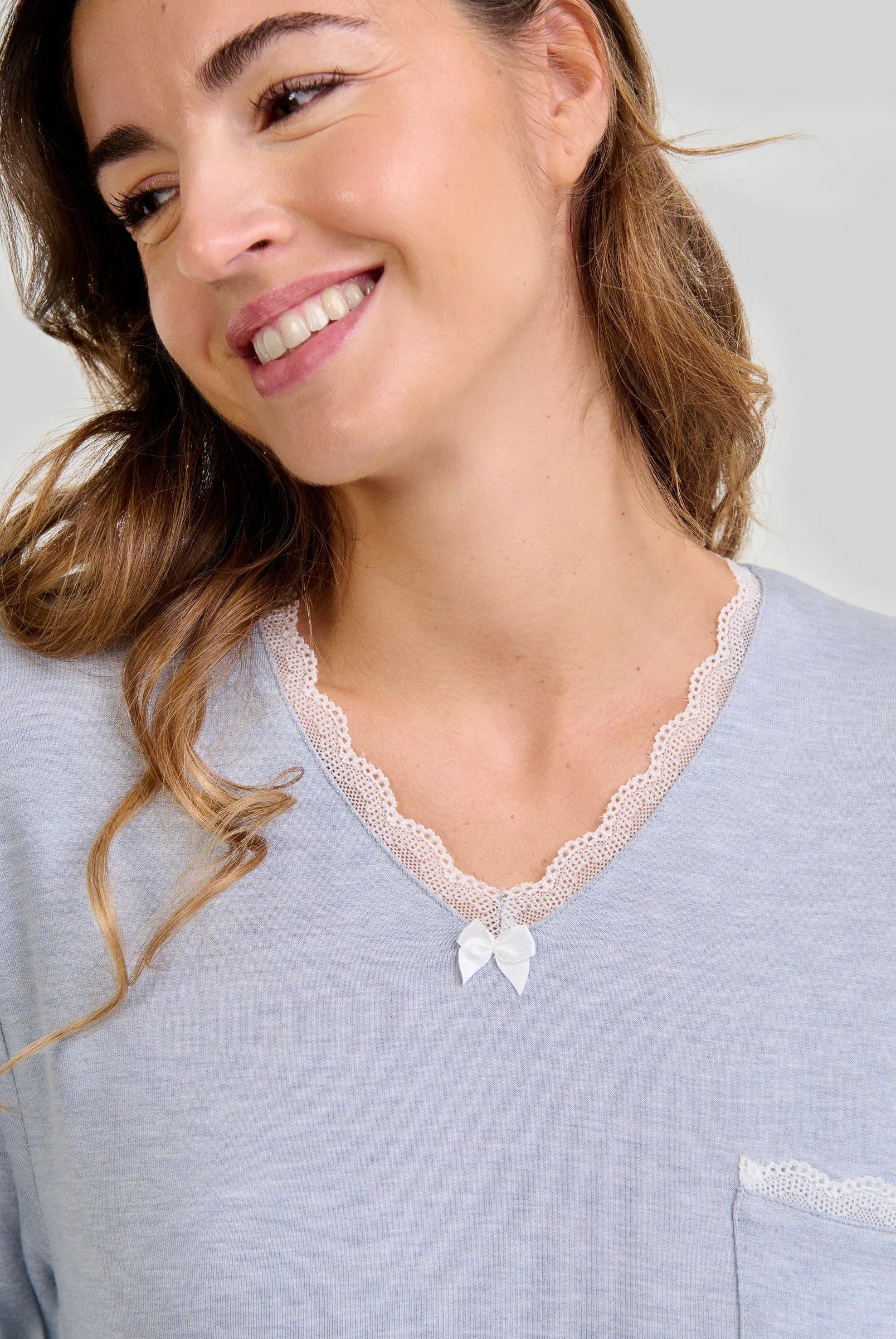 Mujer luce elegante camisón de invierno azul con encaje y lazo en el escote