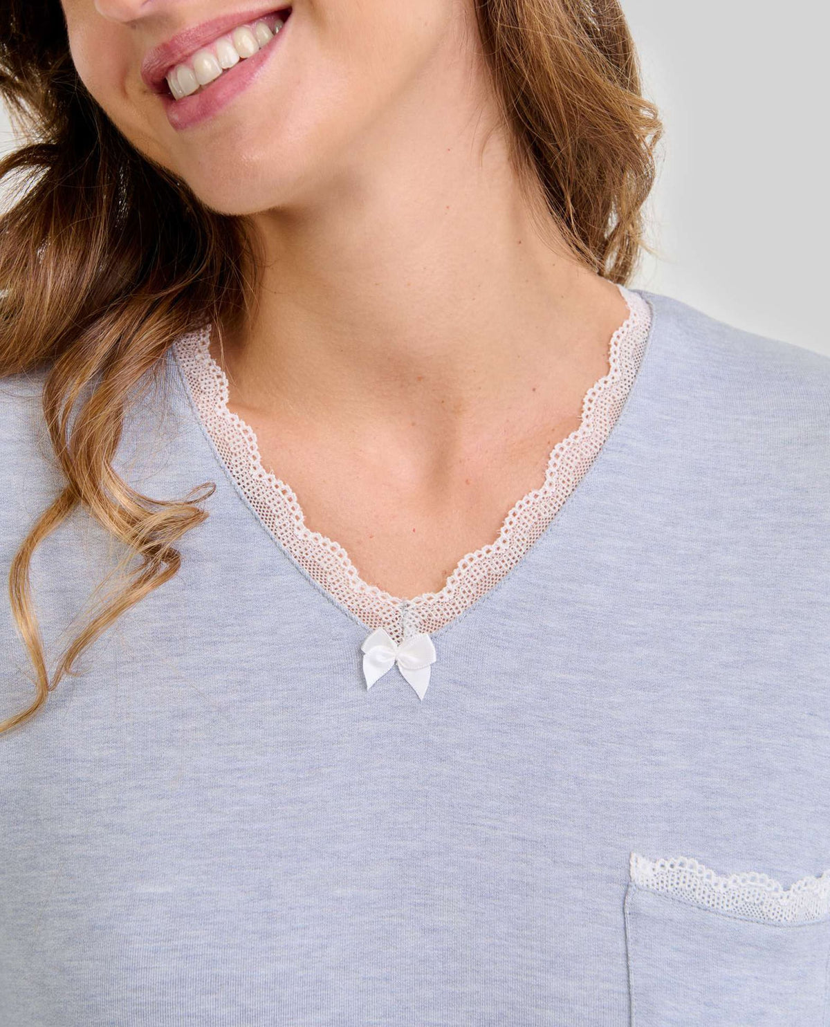 Mujer luce elegante camisón de invierno azul con encaje y lazo en el escote
