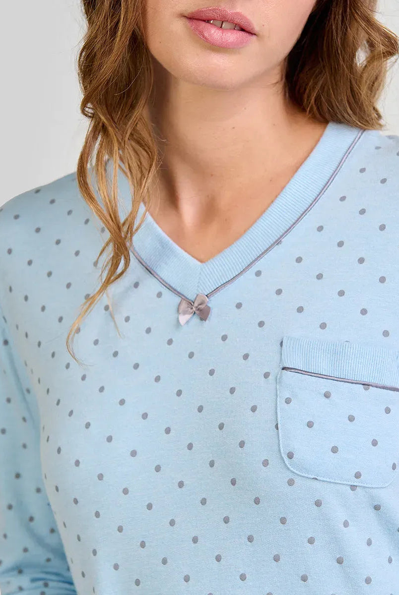Mujer con camisón celeste de lunares grises, cuello en V, lazo pequeño y bolsillo en el pecho