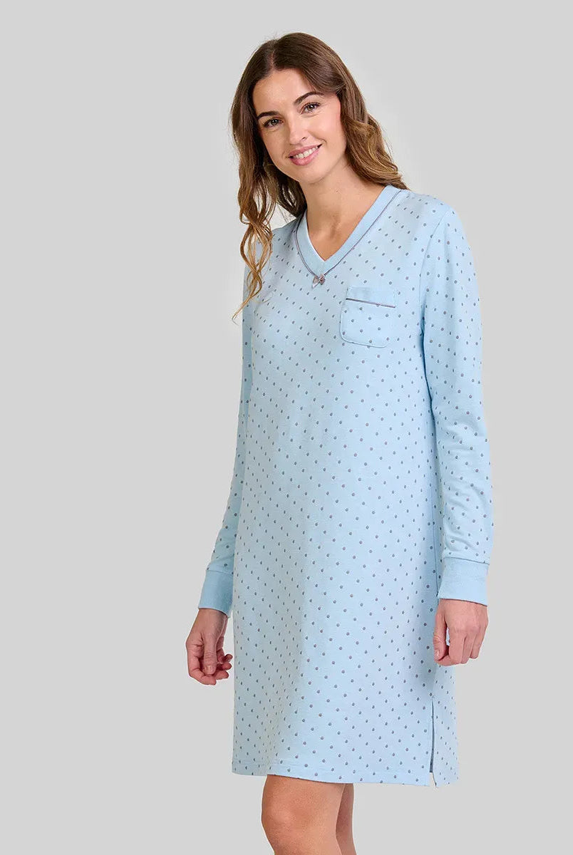 Mujer con camisón azul claro de manga larga, estampado de lunares pequeños y bolsillo