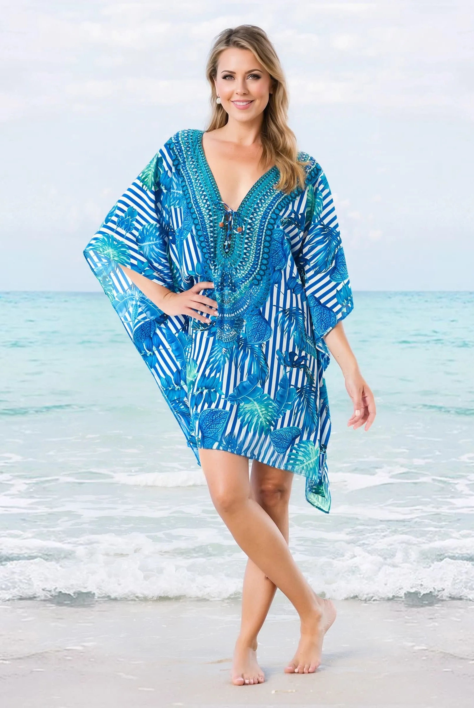 Una mujer luce un caftán azul y blanco con estampado de rayas en la playa, perfecto para el verano