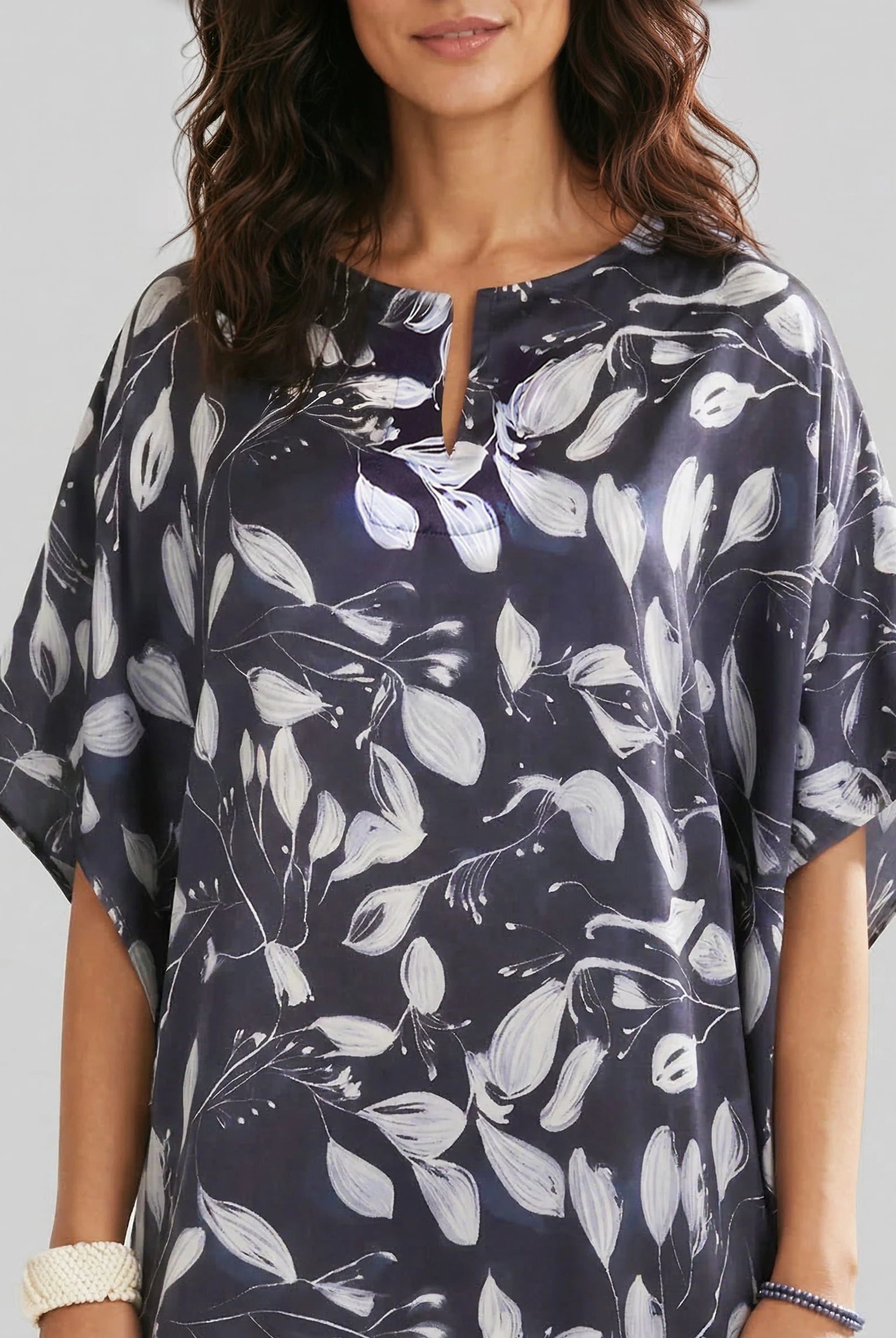 Detalle escote abierto del kaftan de seda estampado marino con flores blancas