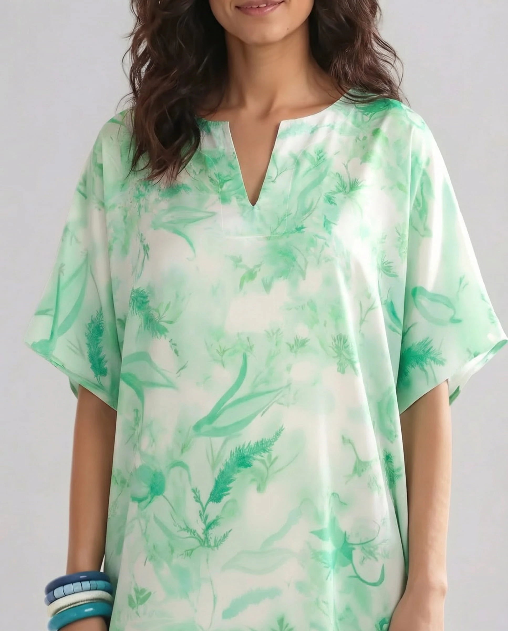 Vista detalle de kaftan de seda natural en tonos verdes y estampado floral con escote abierto y manga al codo