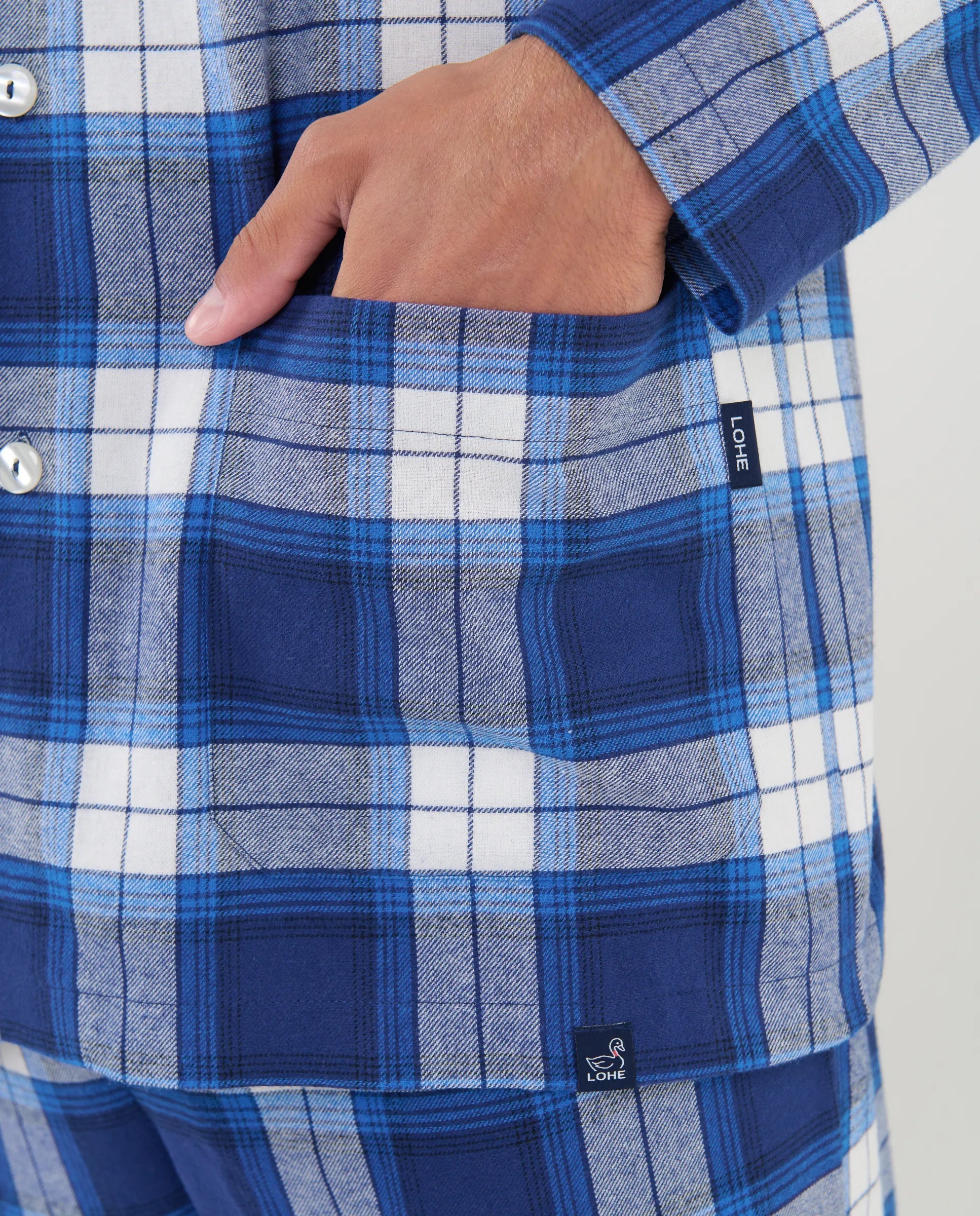Primer plano del estampado de cuadros azules y los botones del pijama camisero de hombre Lohe.