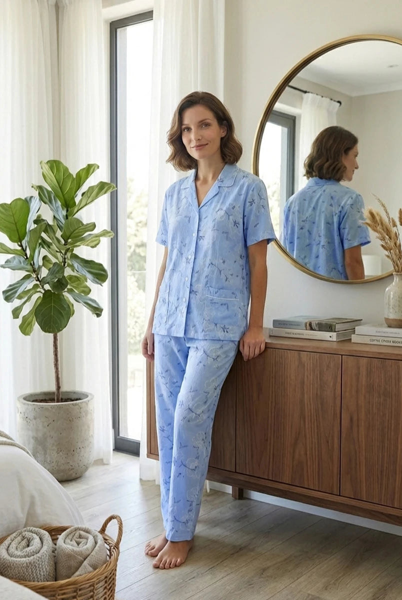 Mujer posa con pijama camisero largo de verano celeste con flores