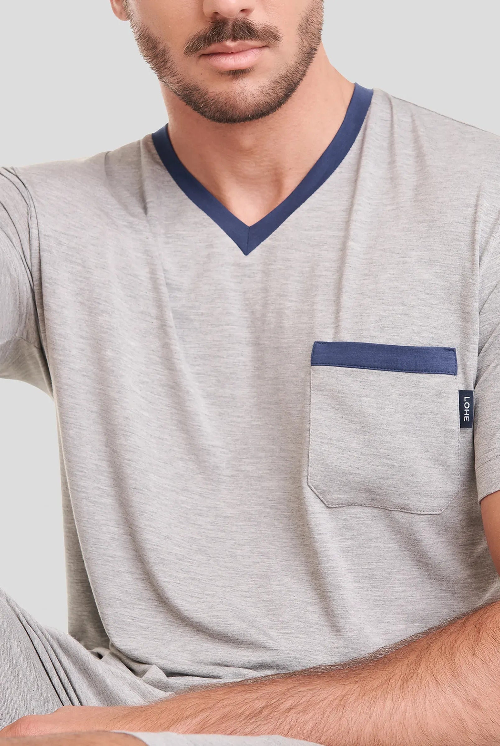 Hombre lleva camiseta de pijama corta de verano a rayas y pantalones cortos azules.