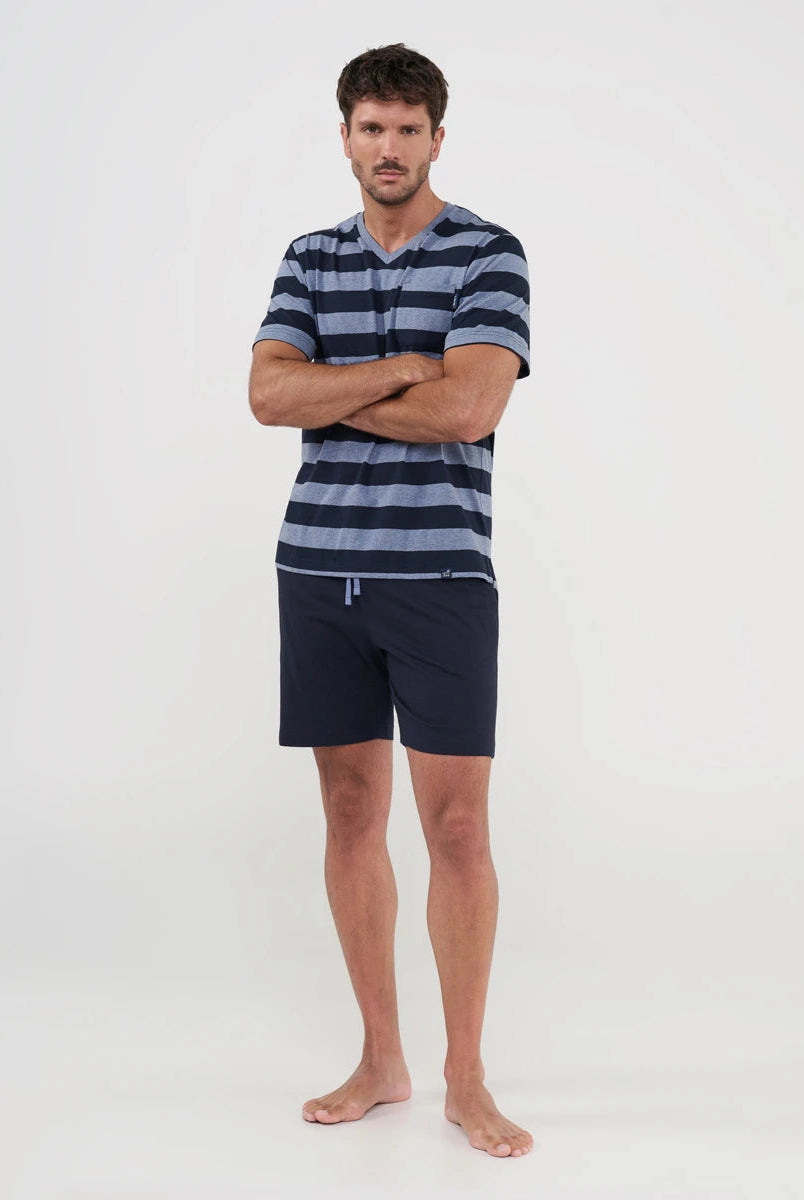 Hombre posa con pijama corto de verano con top marino a rayas y pantalón liso marino
