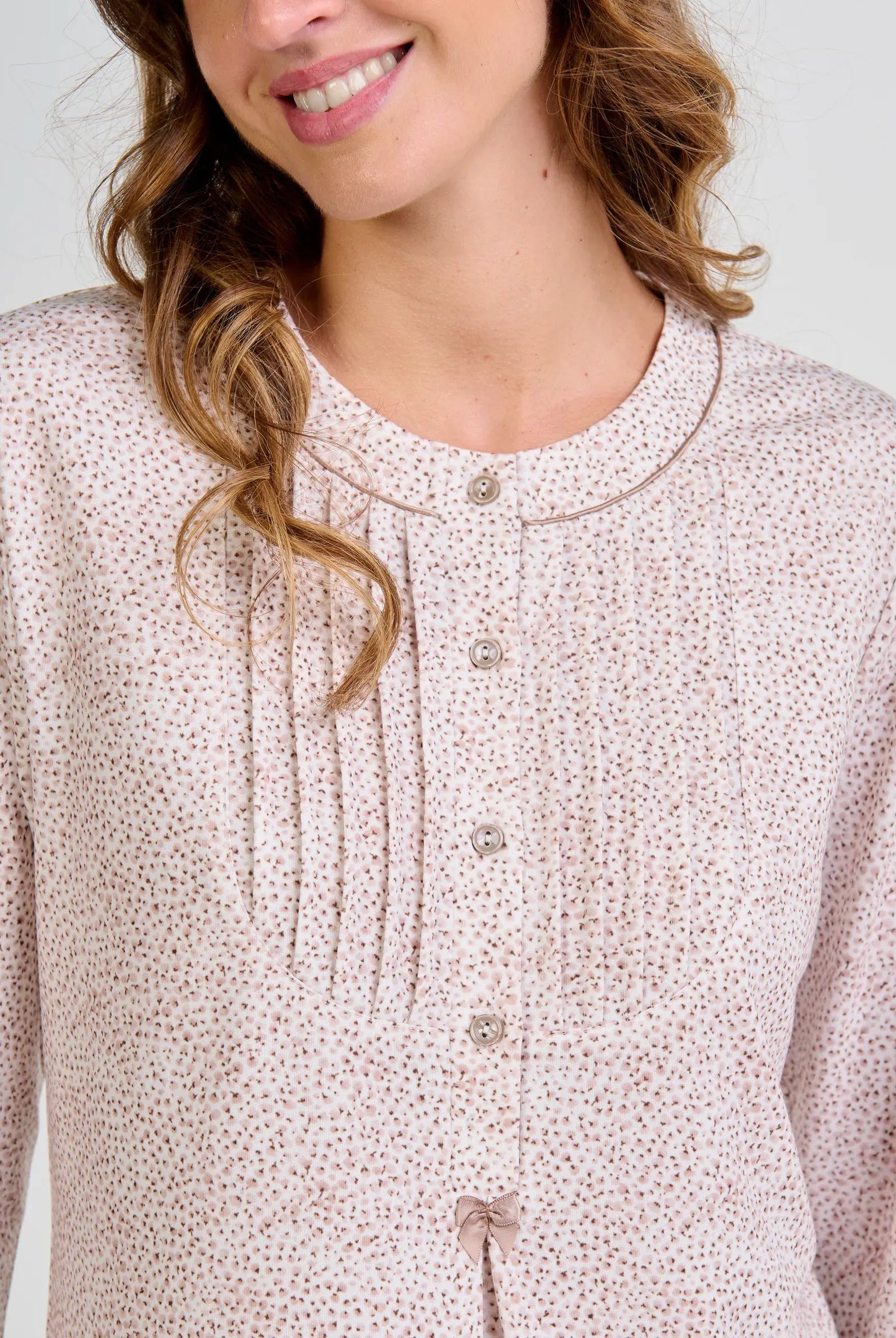 Mujer sonriente con blusa de pijama abotonada de color camel estampada con florecitas y detalle frontal plisado