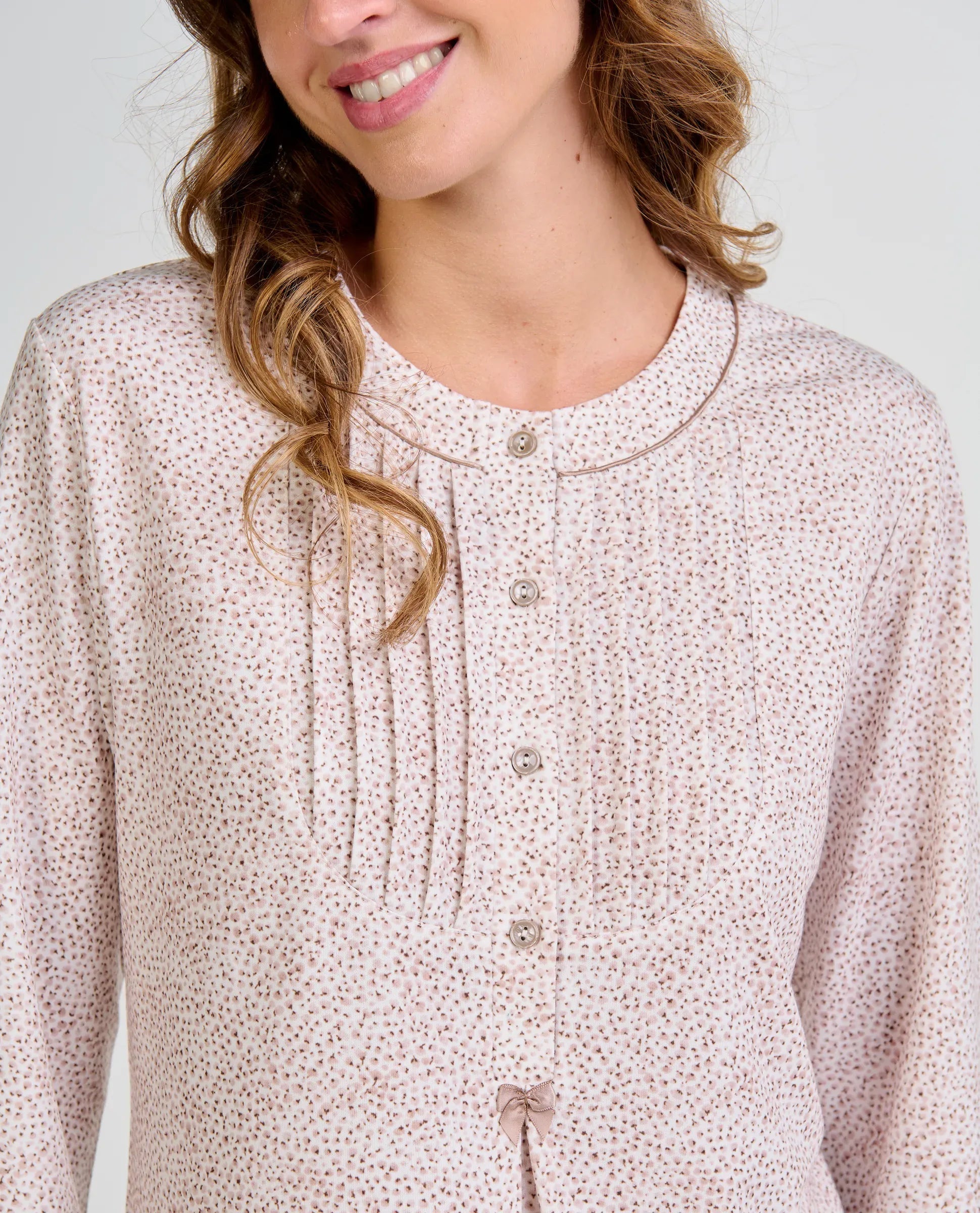 Mujer sonriente con blusa de pijama abotonada de color camel estampada con florecitas y detalle frontal plisado