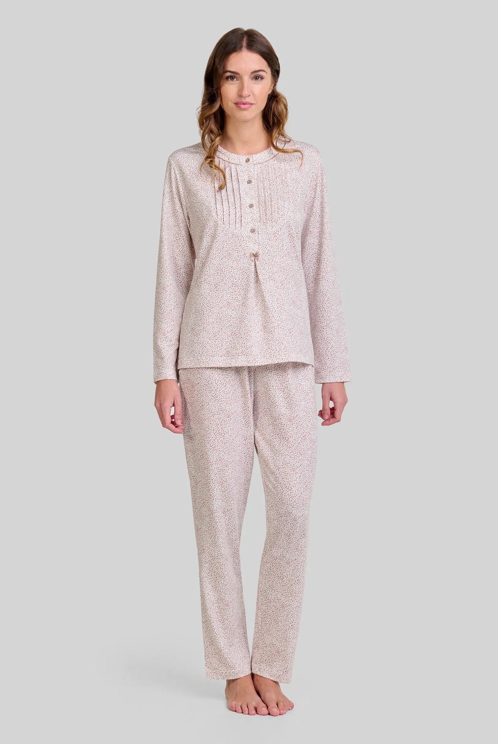 Mujer posando con sutil y elegante pijama de manga larga y pantalón de estampado floral camel.