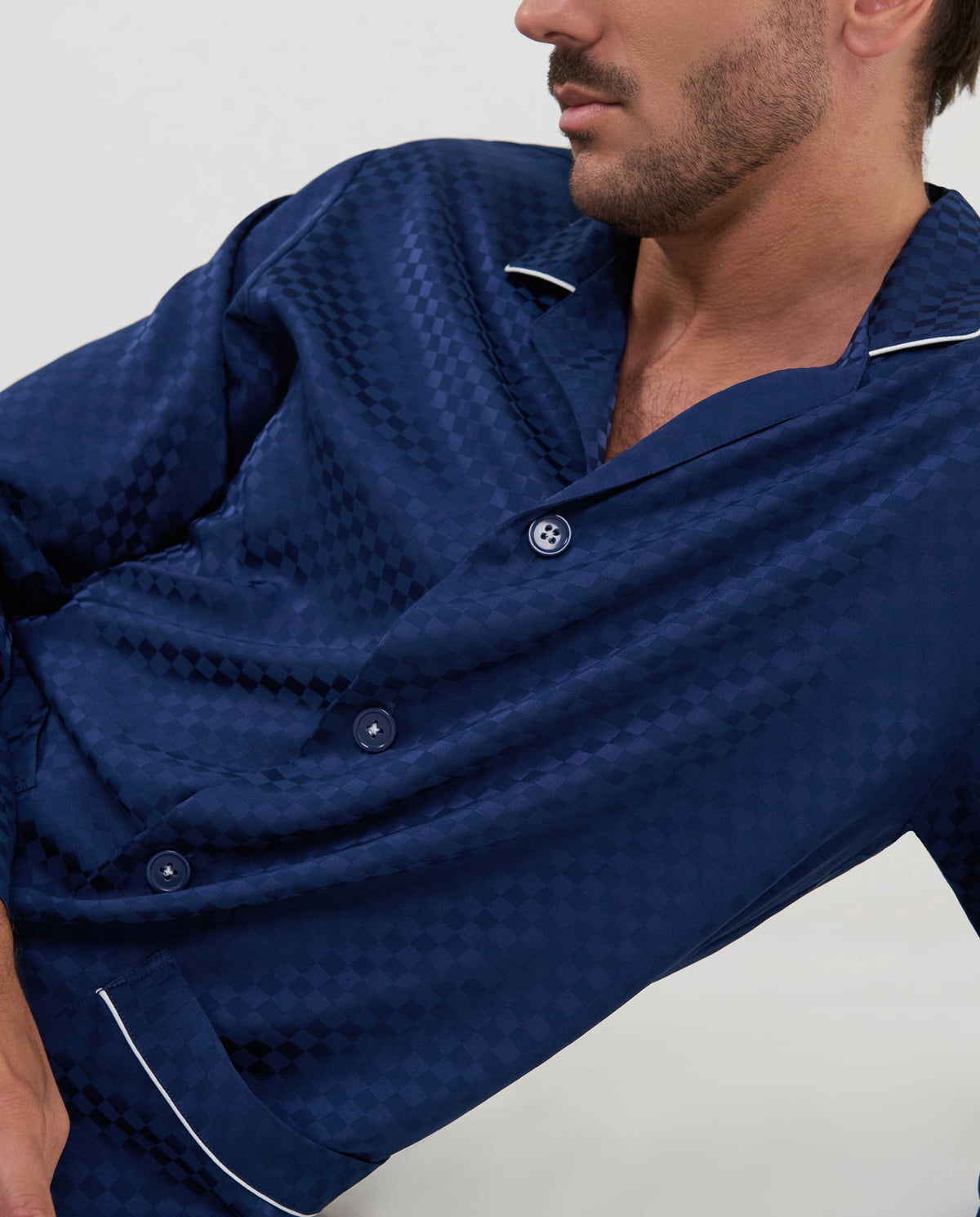 Primer plano del tejido jacquard con patrón de cuadros marino y detalle de botones en el pijama de hombre.