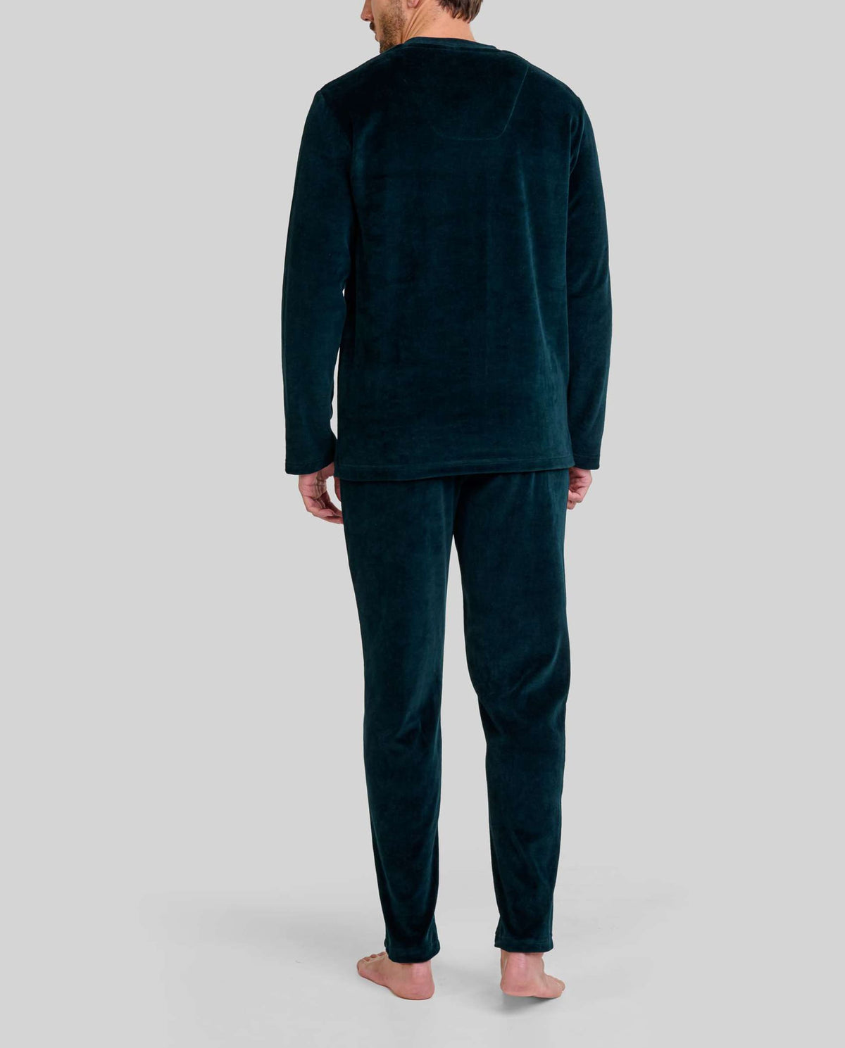 hombre de espaldas con confortable pijama largo de terciopelo liso verde con bolsillos laterales
