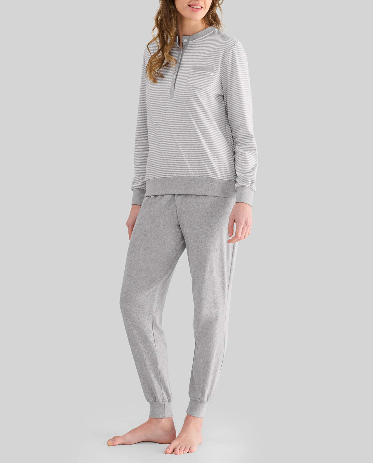 Mujer con pijama largo a rayas grises y cuello pata en el top y pantalón largo vigoré gris