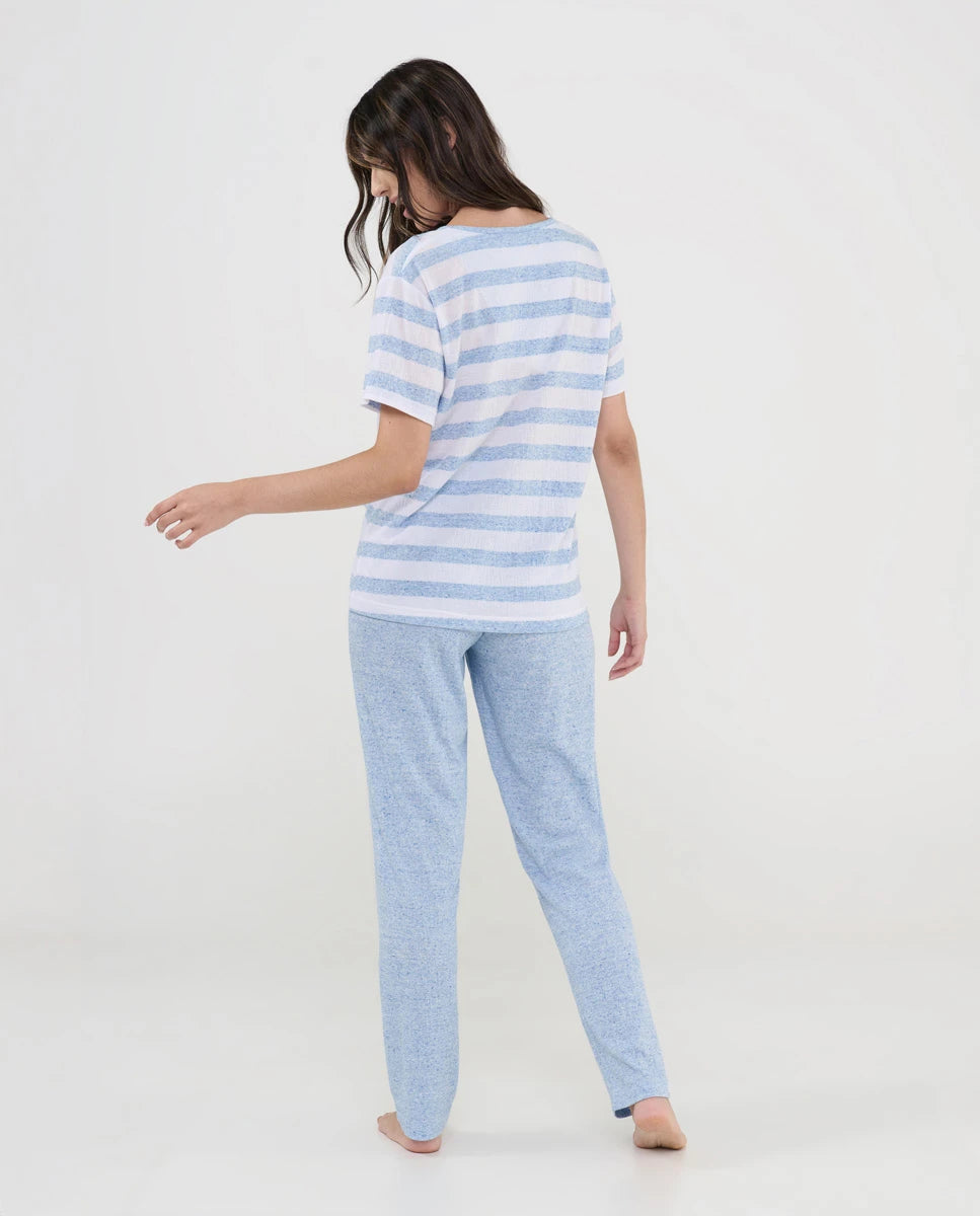 Mujer de espaldas con pijama largo de verano con camiseta celeste de rayas y pantalón liso a juego