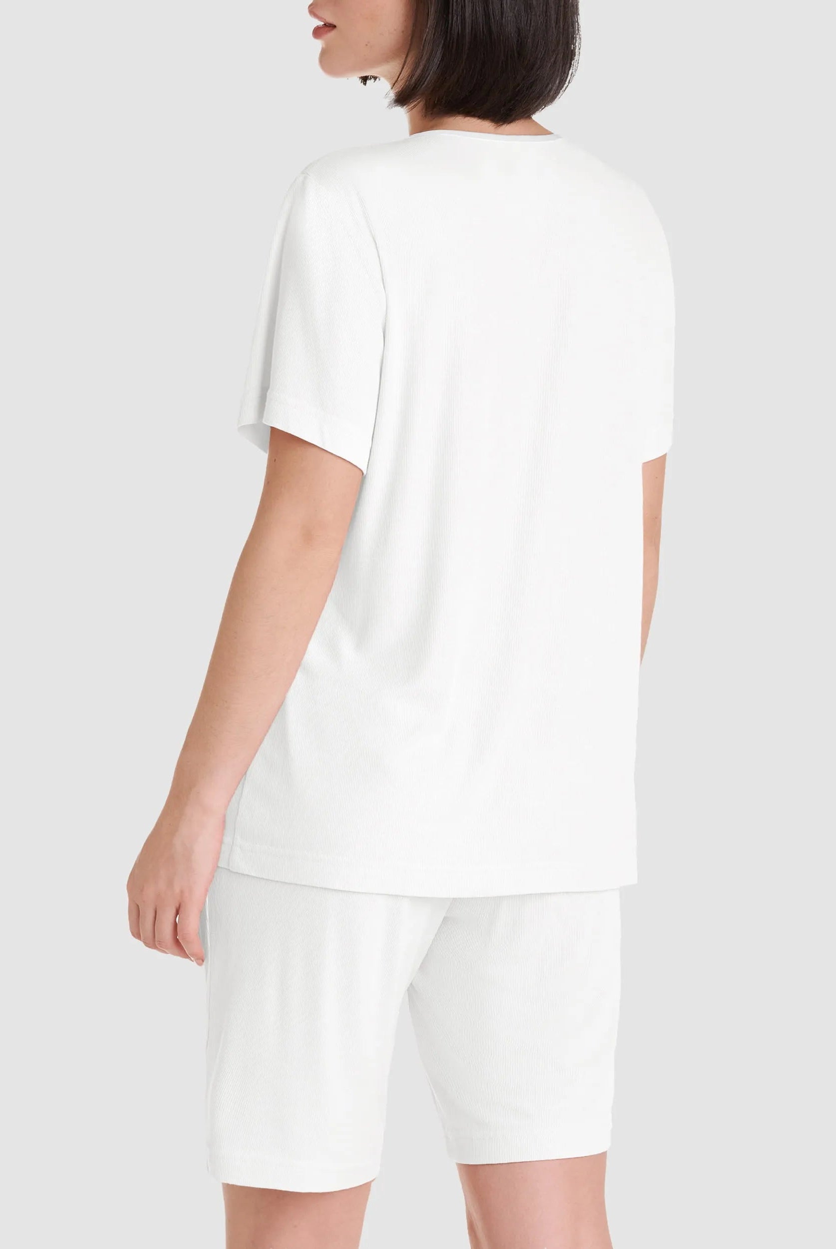 Vista detalle de mujer con camiseta de manga corta a rayas para dormir este verano y cuello con botones rosas