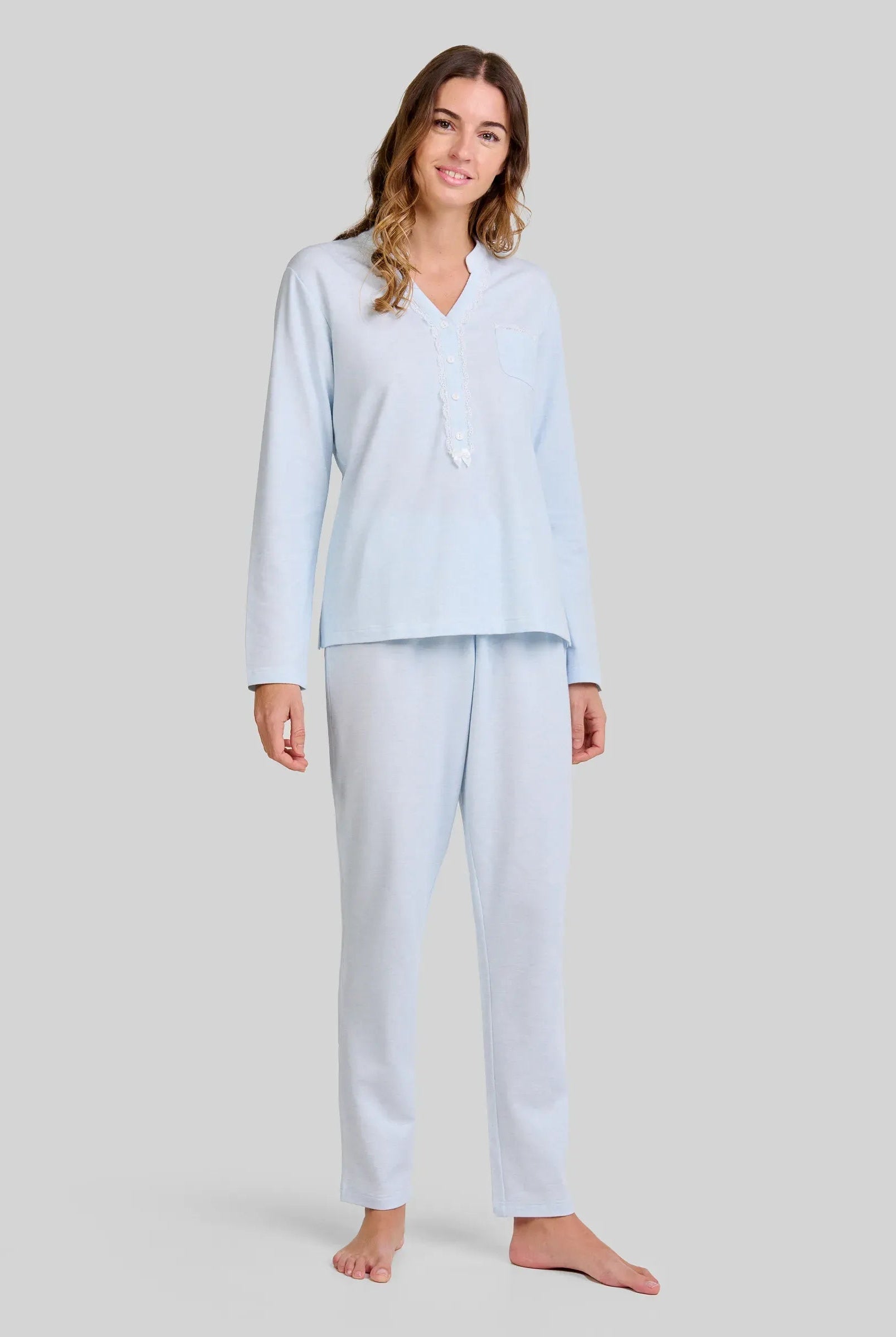 Mujer con pijama largo lencero color celeste de cuello abierto con puntilla y lazo