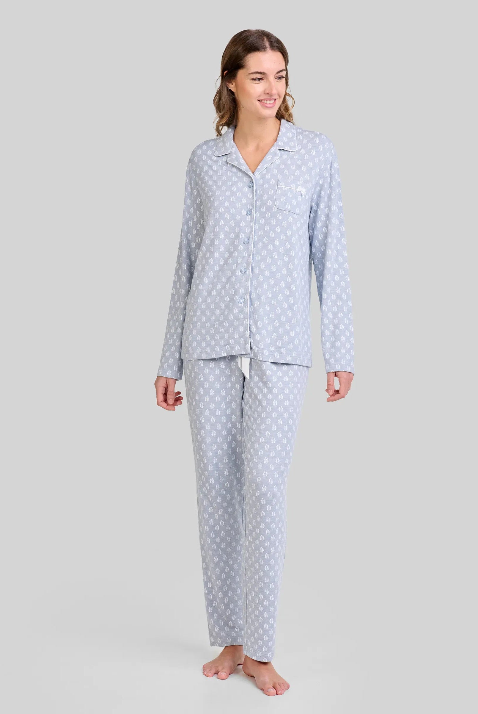 Mujer con pijama azul acero y estampado de hojas blancas. Moda cómoda para dormir y descansar.