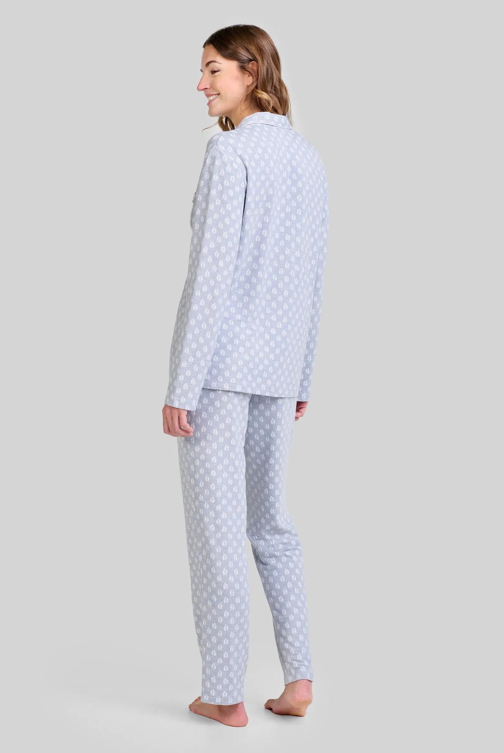 Mujer de espaldas con pijama azul claro de manga larga con estampado hojas blancas, moda cómoda.