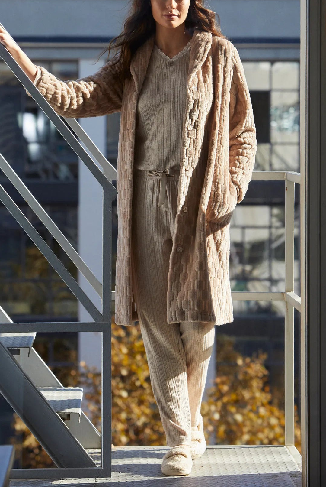 Mujer lleva bata beige texturizada y conjunto de pijama canale camel y pantuflas
